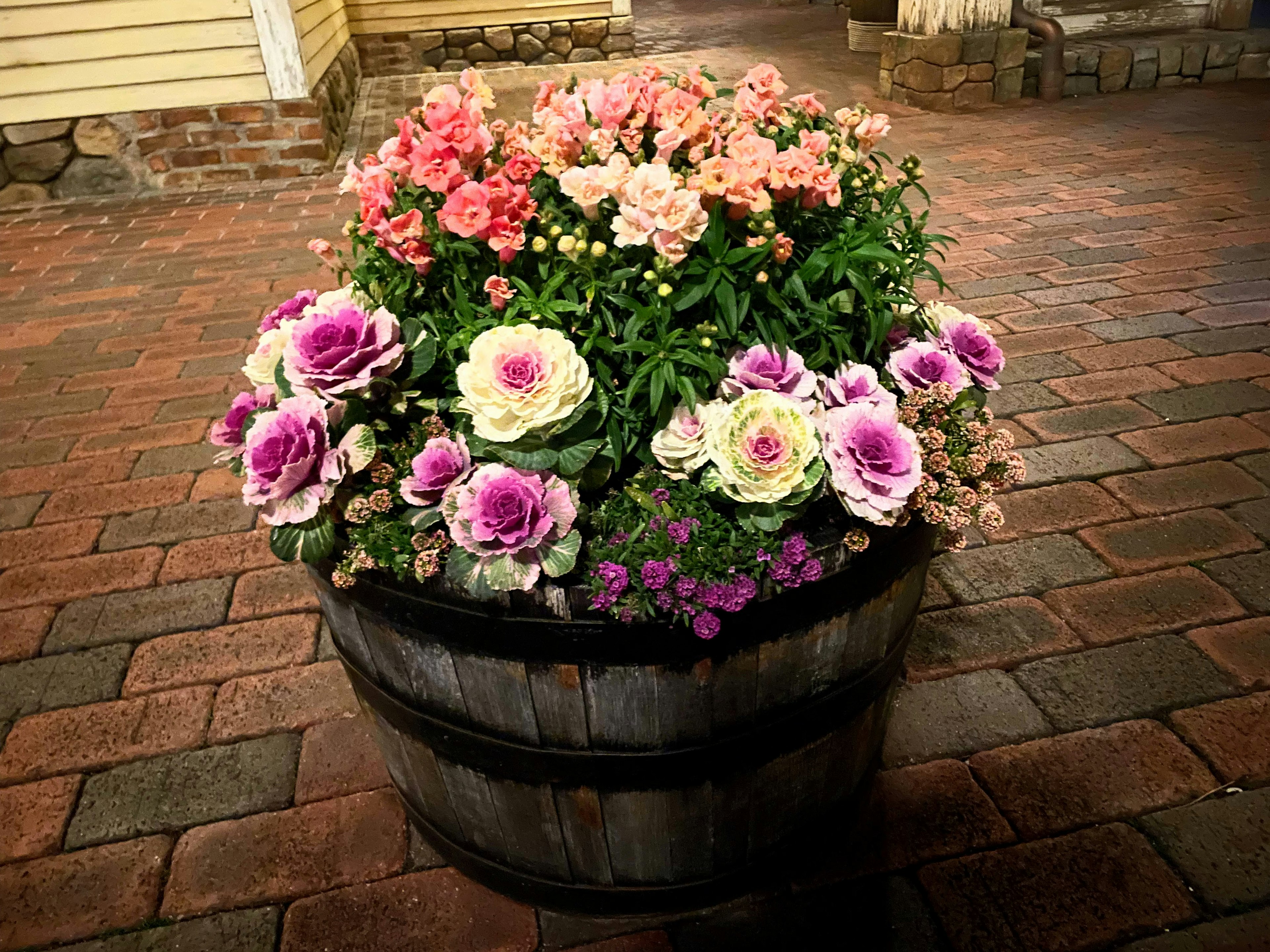 Ein Holzfass gefüllt mit bunten blühenden Blumen