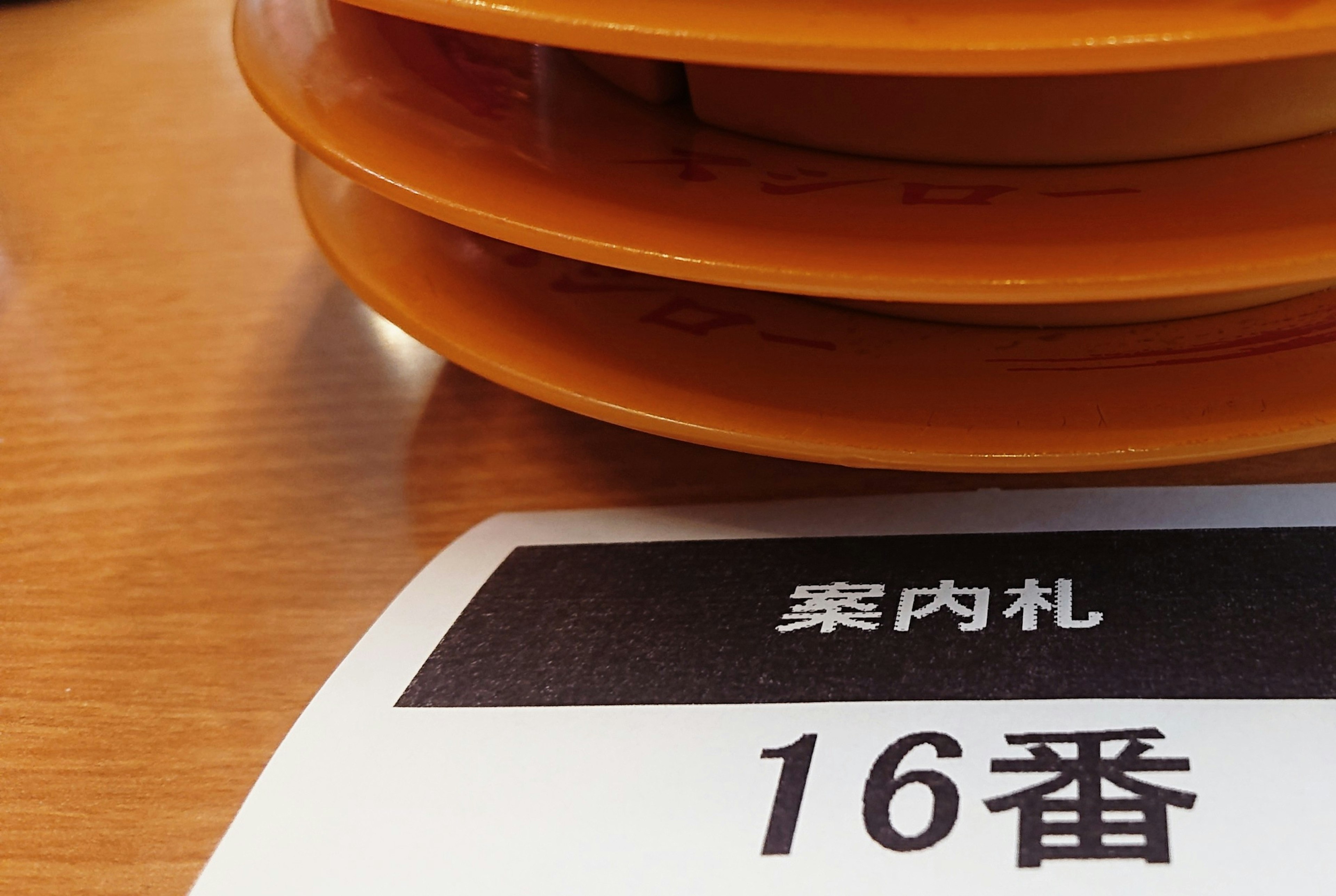 A stack of orange plates on a table with a number tag 16