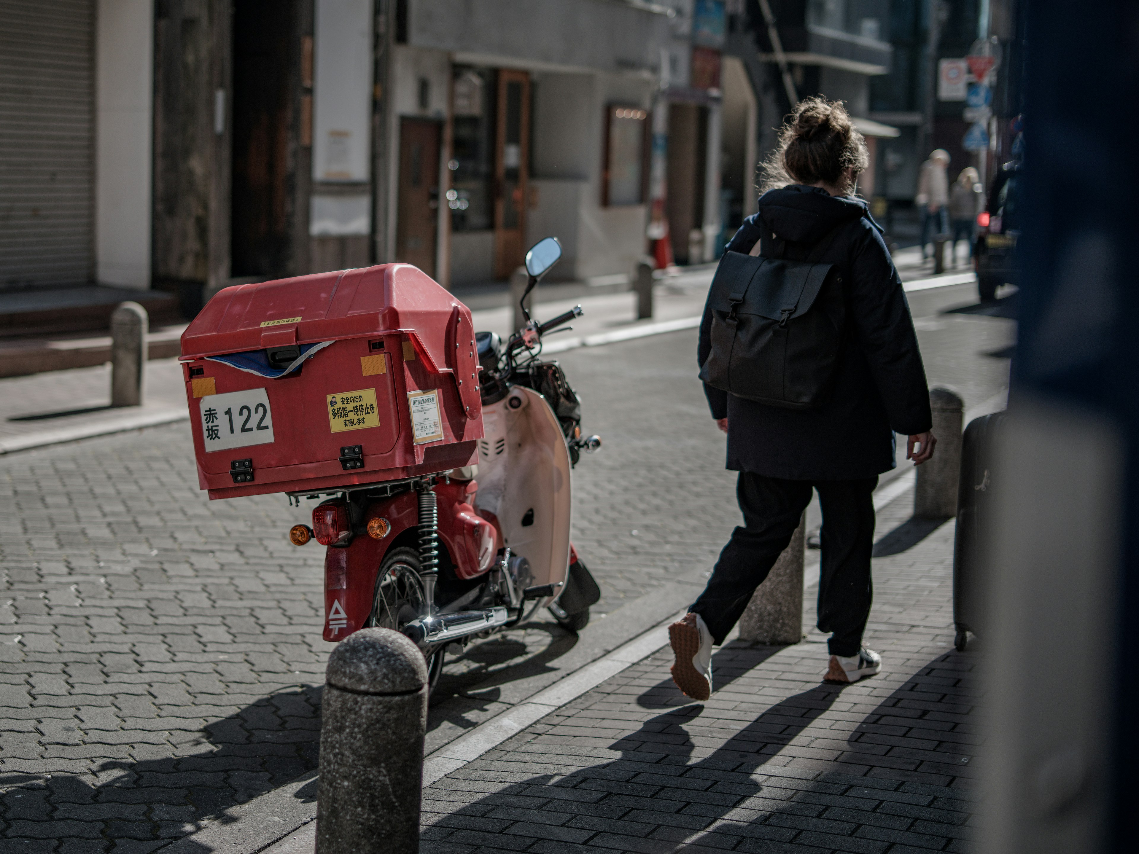 赤い郵便配達バイクと歩く人