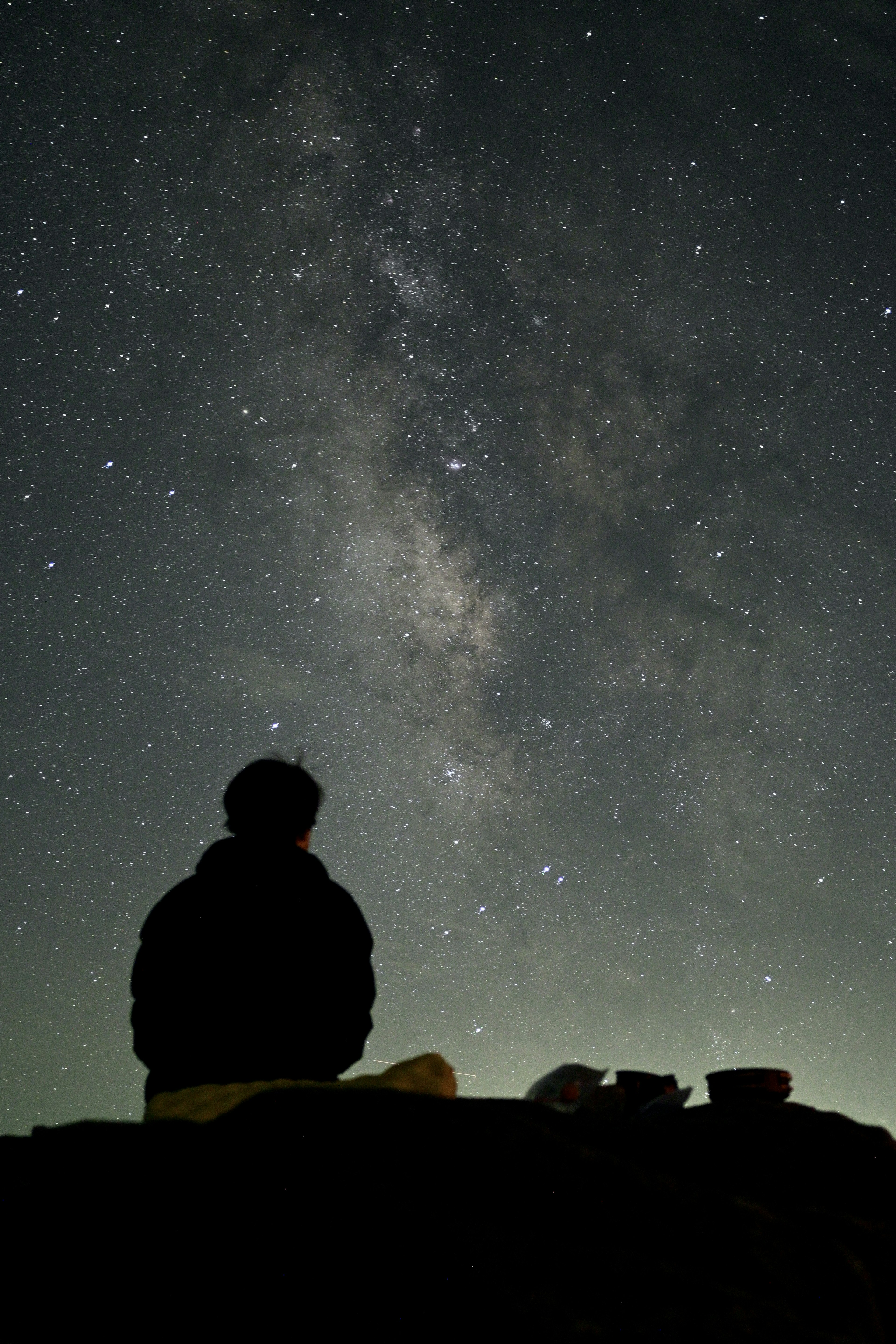 星空の下で座っている人物と銀河の美しい景色