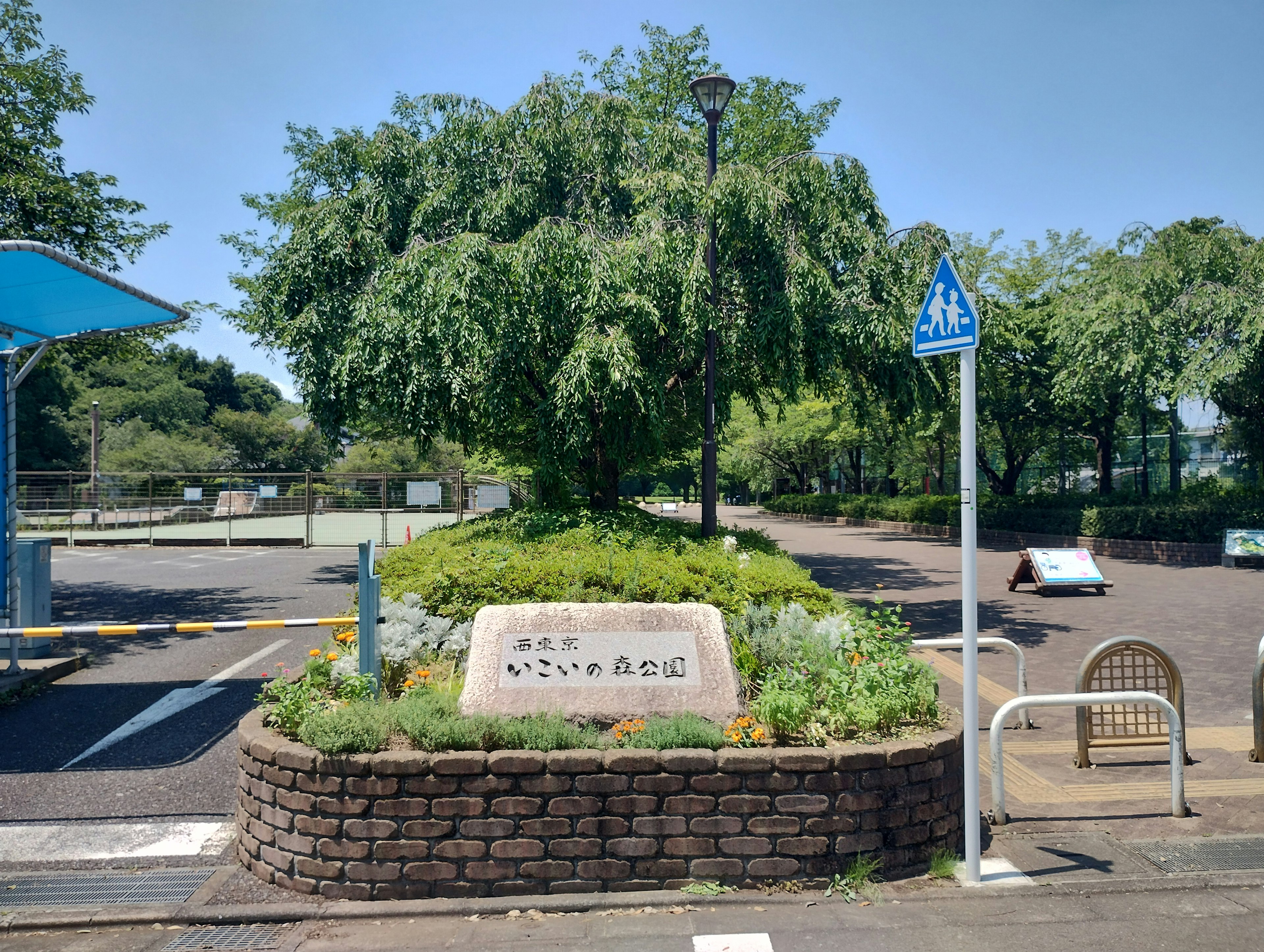 公園の入り口にある石の看板と緑豊かな植栽