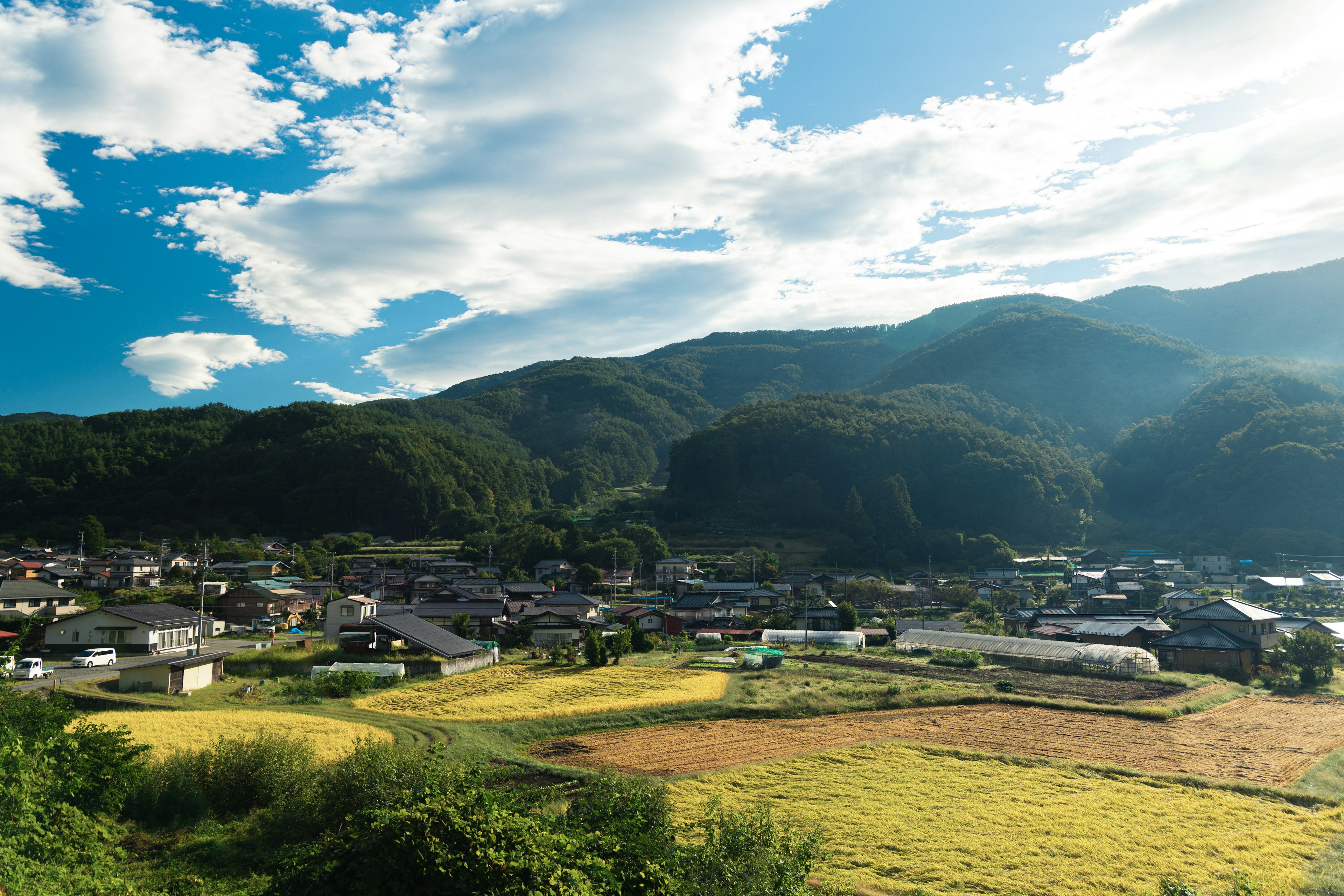 山々に囲まれた田舎の風景で青空と白い雲が広がる