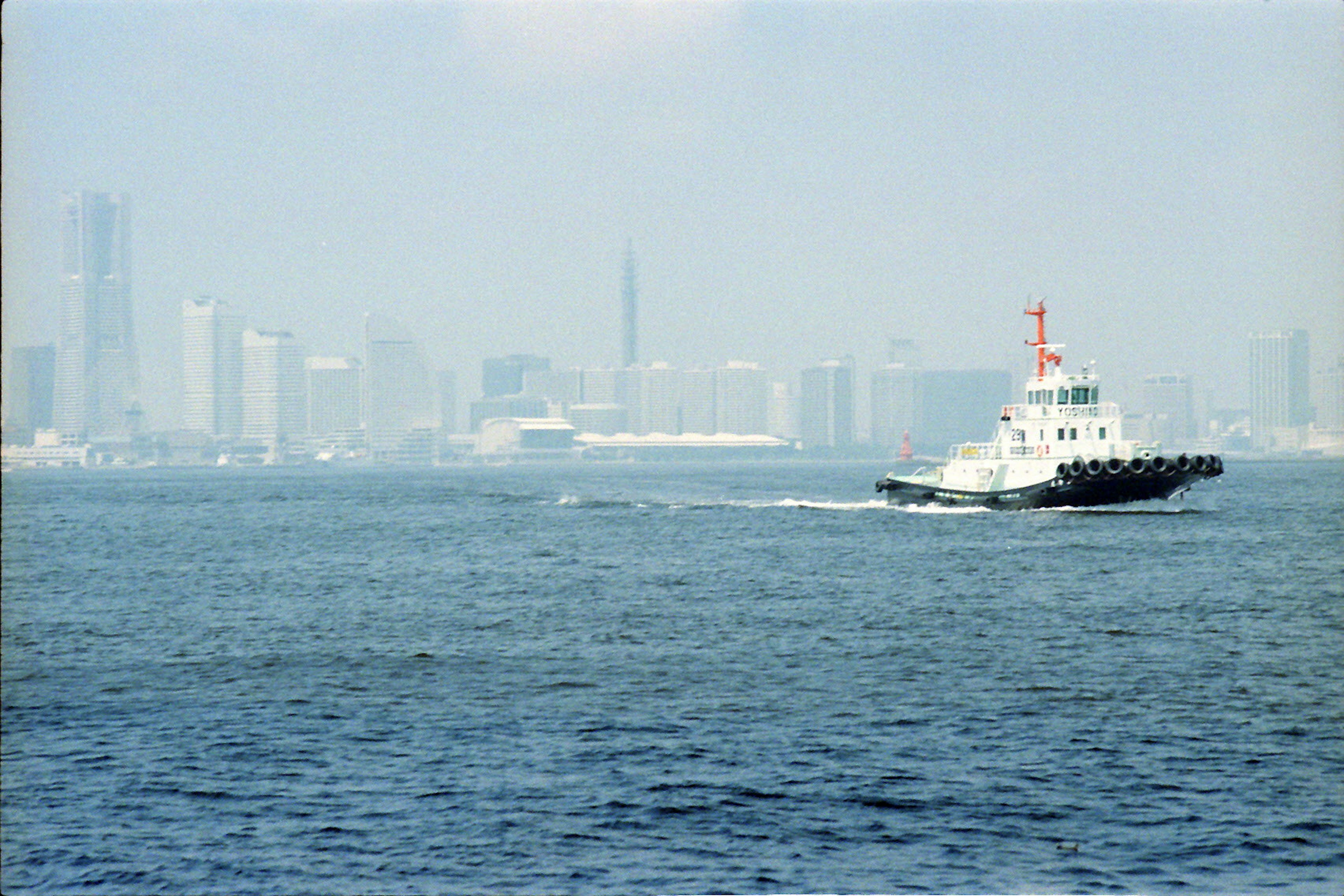 海を航行するタグボートとぼんやりとした都市の背景