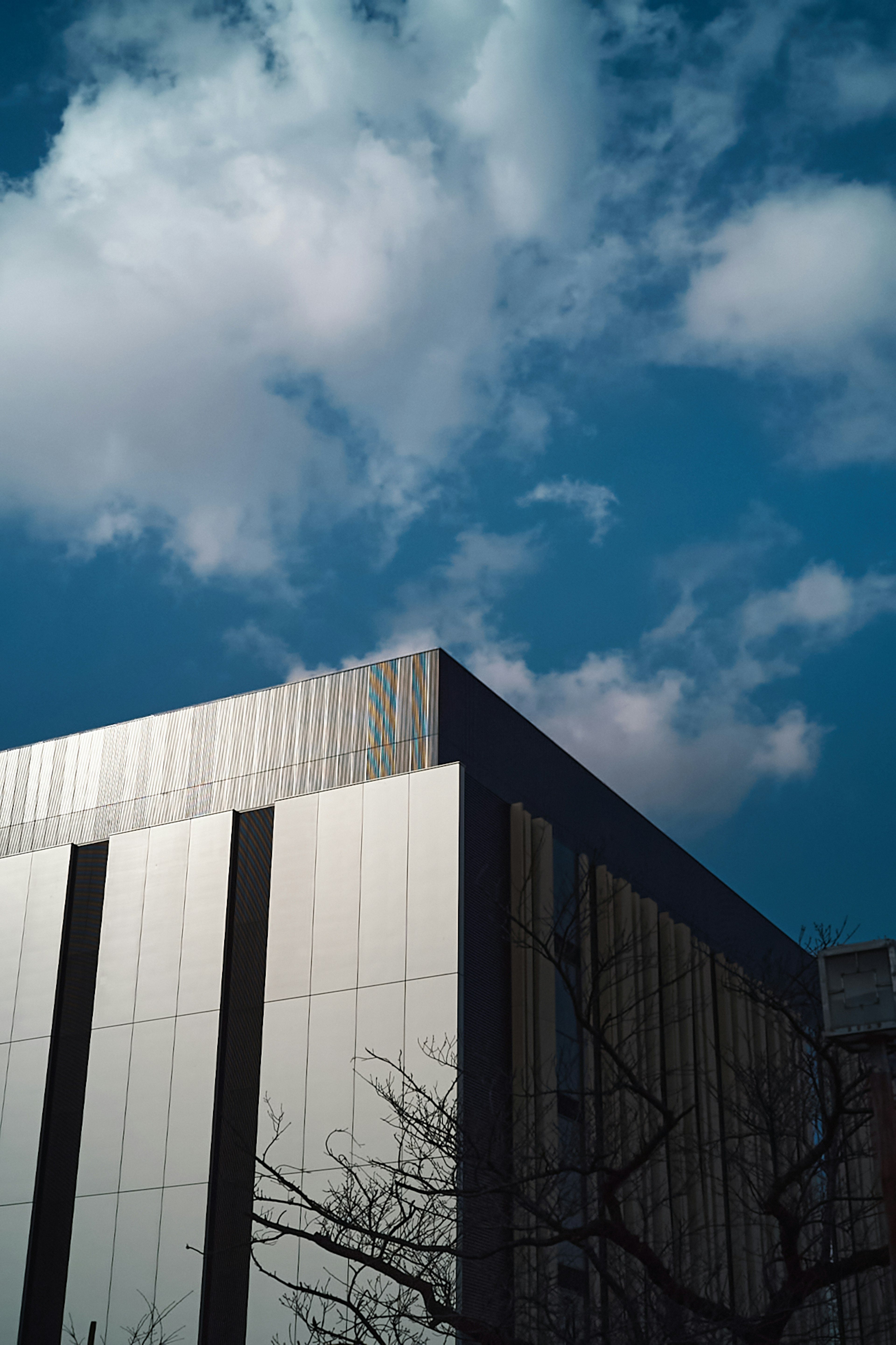 Ecke eines modernen Gebäudes vor blauem Himmel mit weißen Wolken