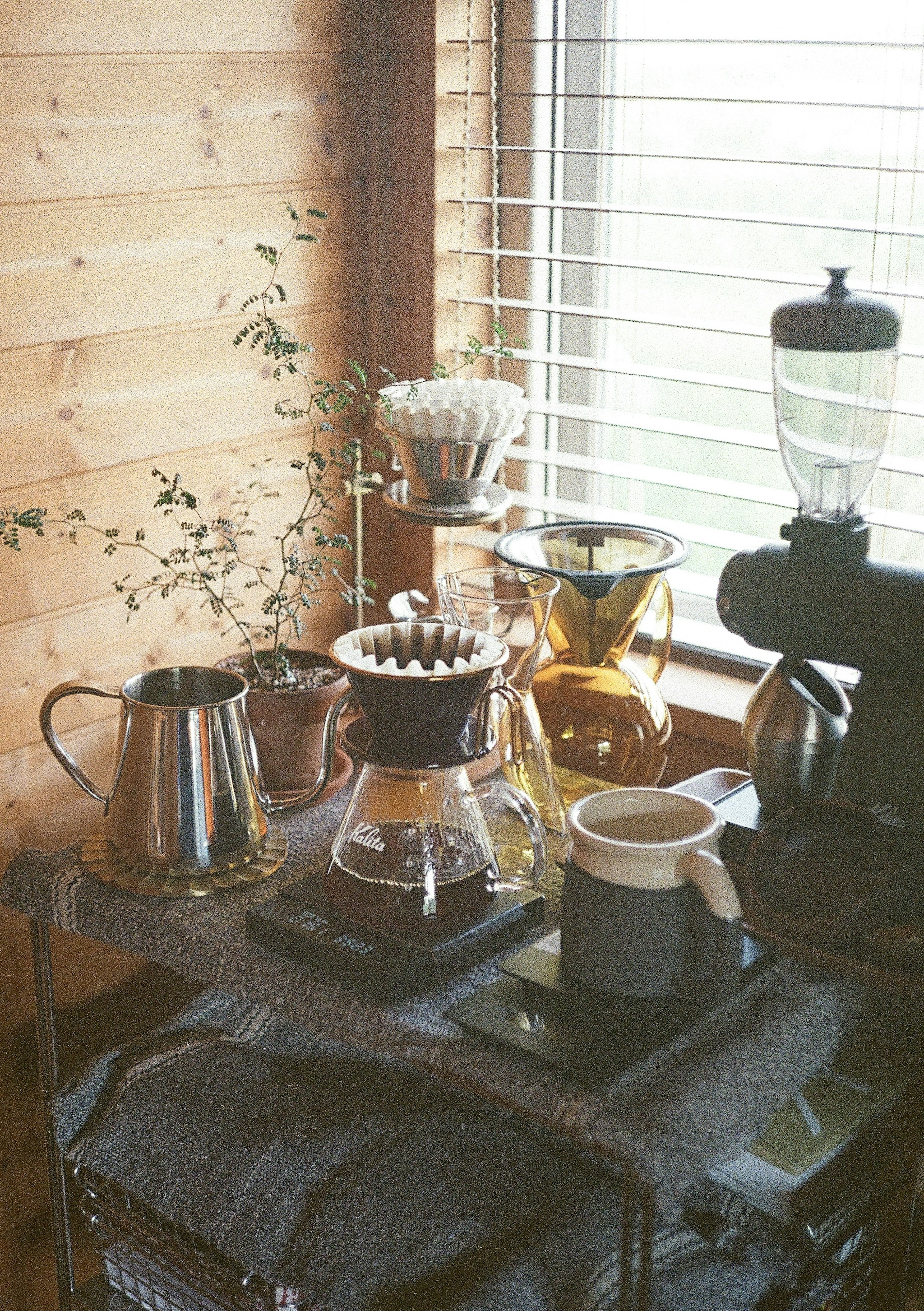 Setup di caffè vicino a una finestra con pareti in legno con una caffettiera e un filtro per caffè