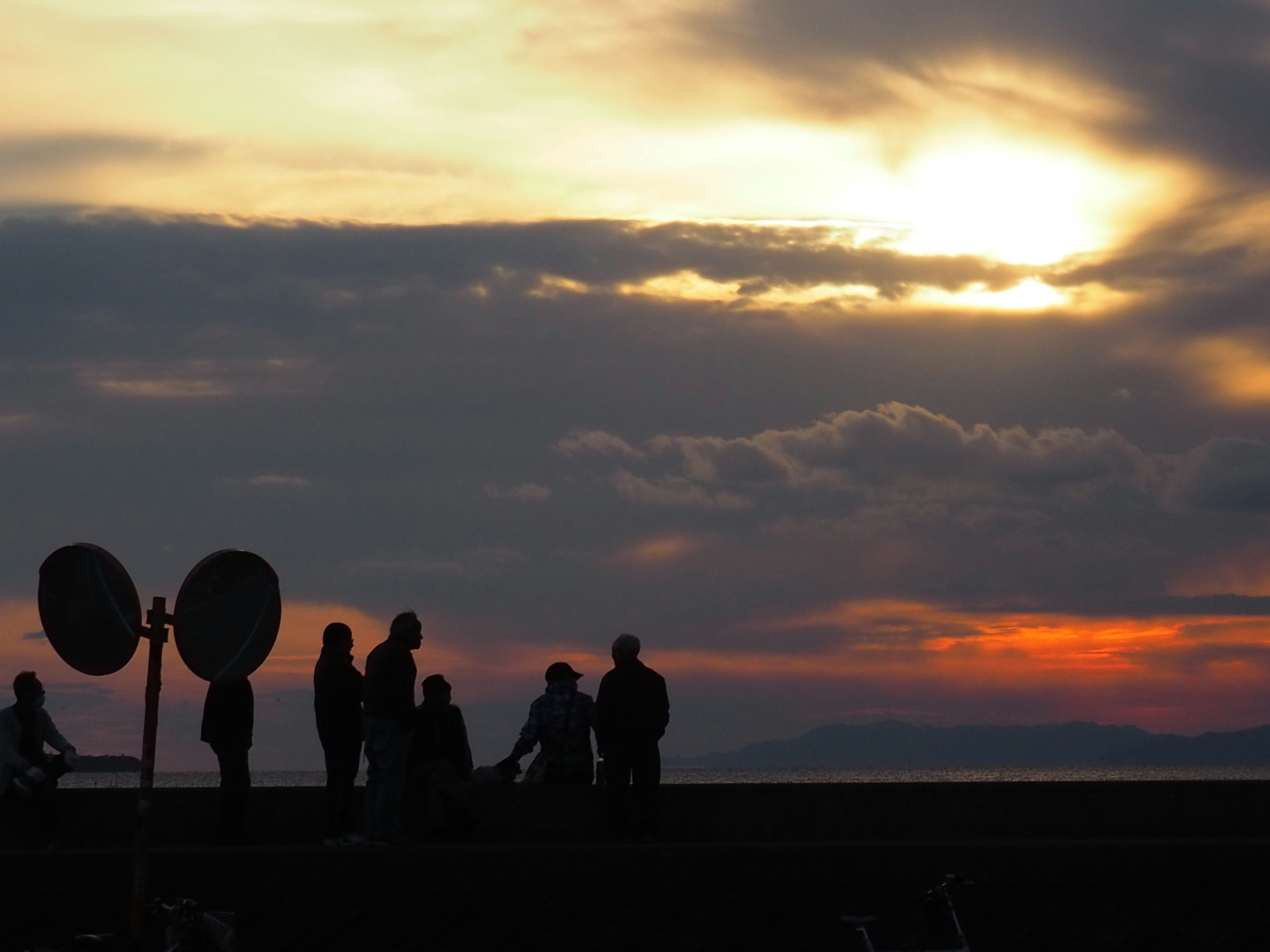 Siluetas de personas contra un atardecer con nubes