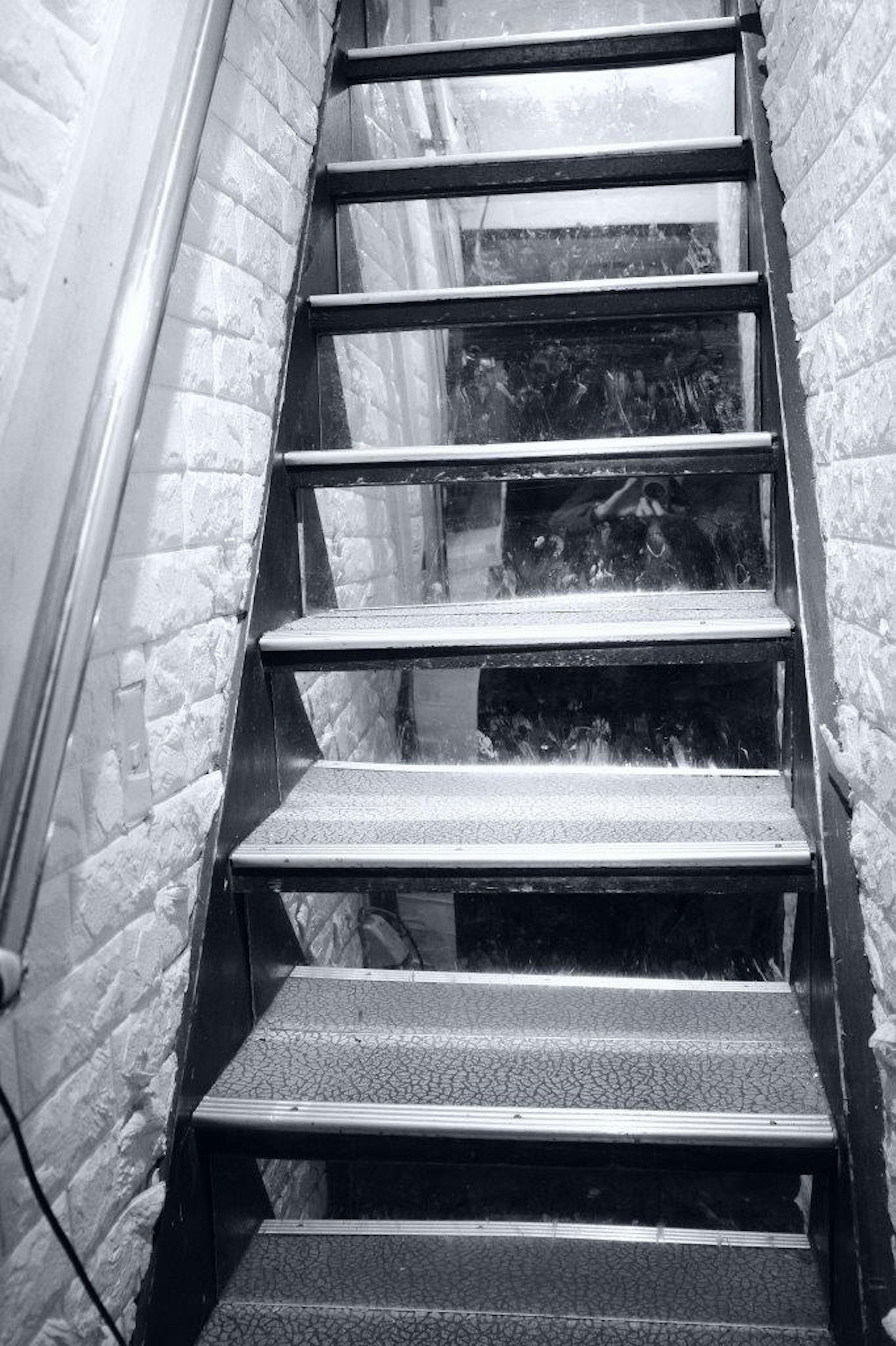 A view of a staircase from above featuring metal steps and a white brick wall