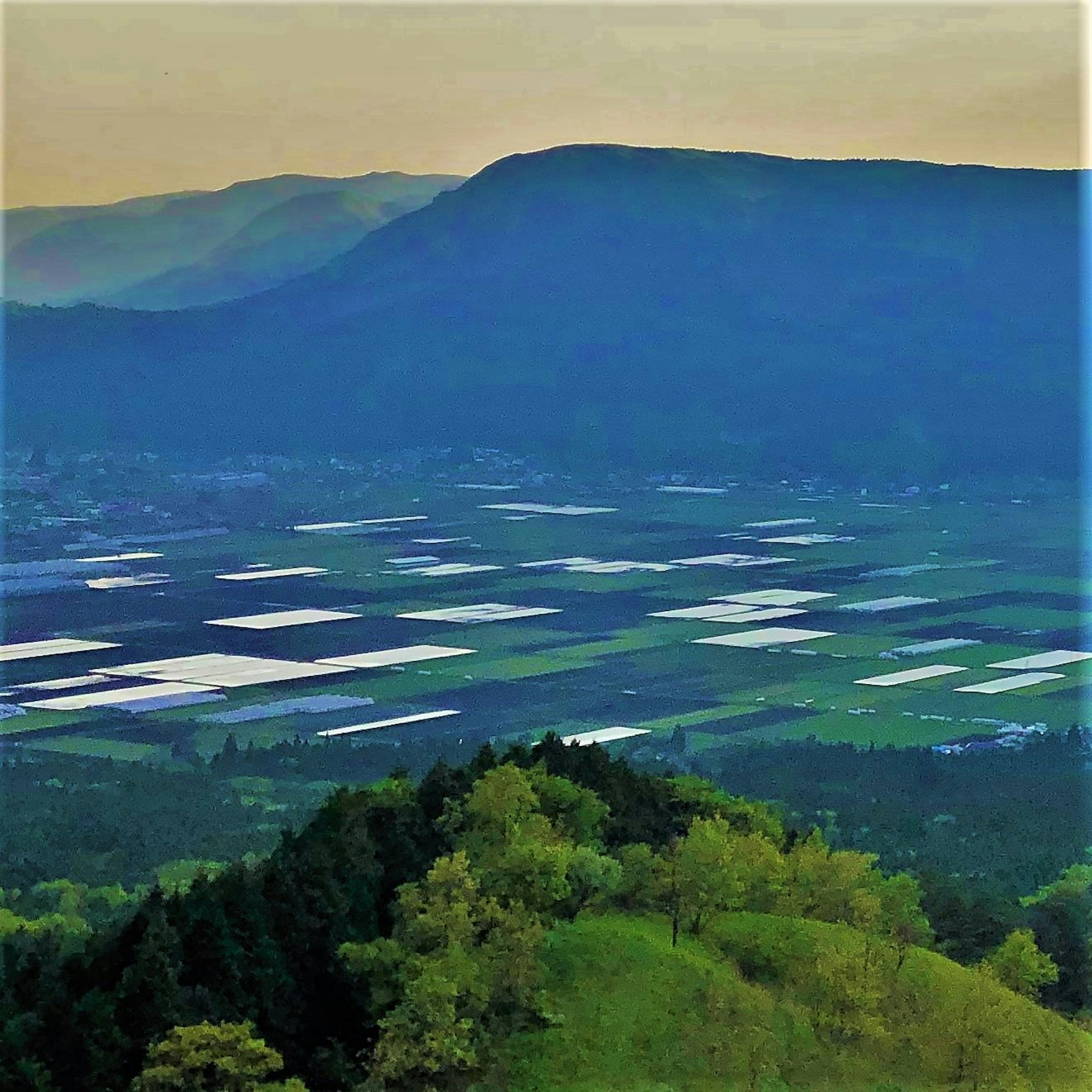 美しい山々と広がる農地の風景 緑の丘と白いビニールハウスが見える