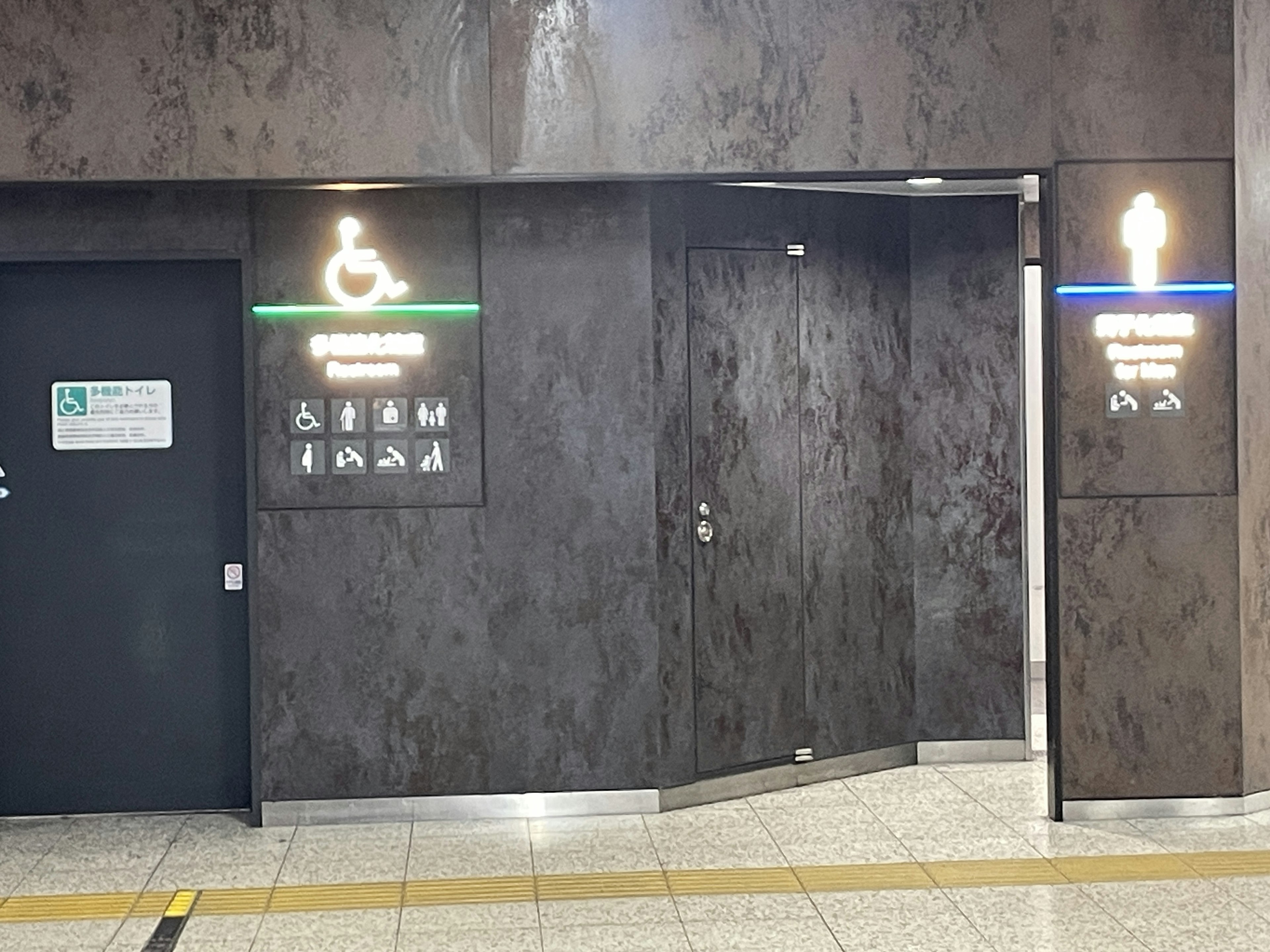 Entrance to a restroom with accessibility sign and directional indicator