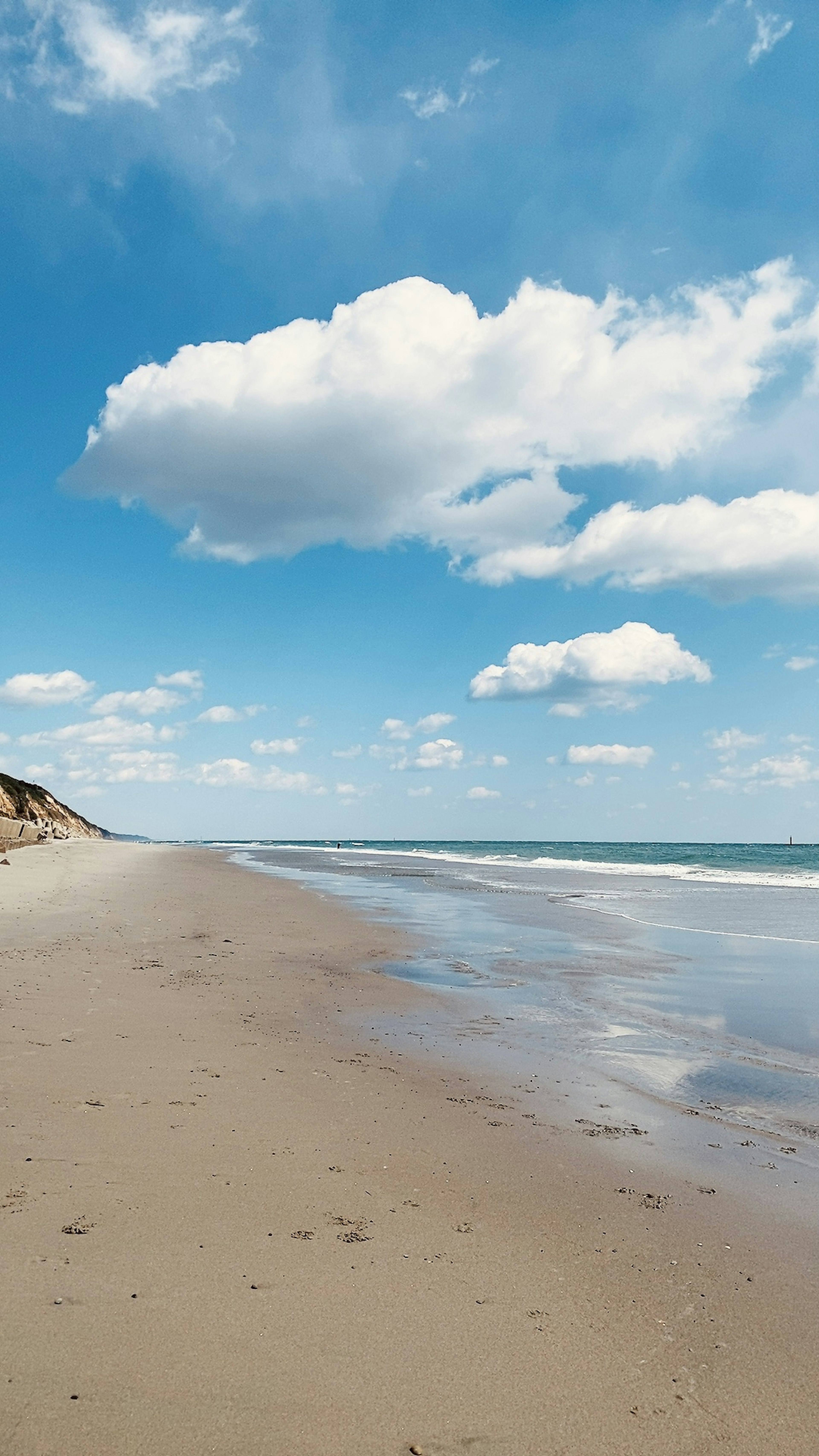 Strandszene mit blauem Himmel und weißen Wolken Ufer mit nassem Sand