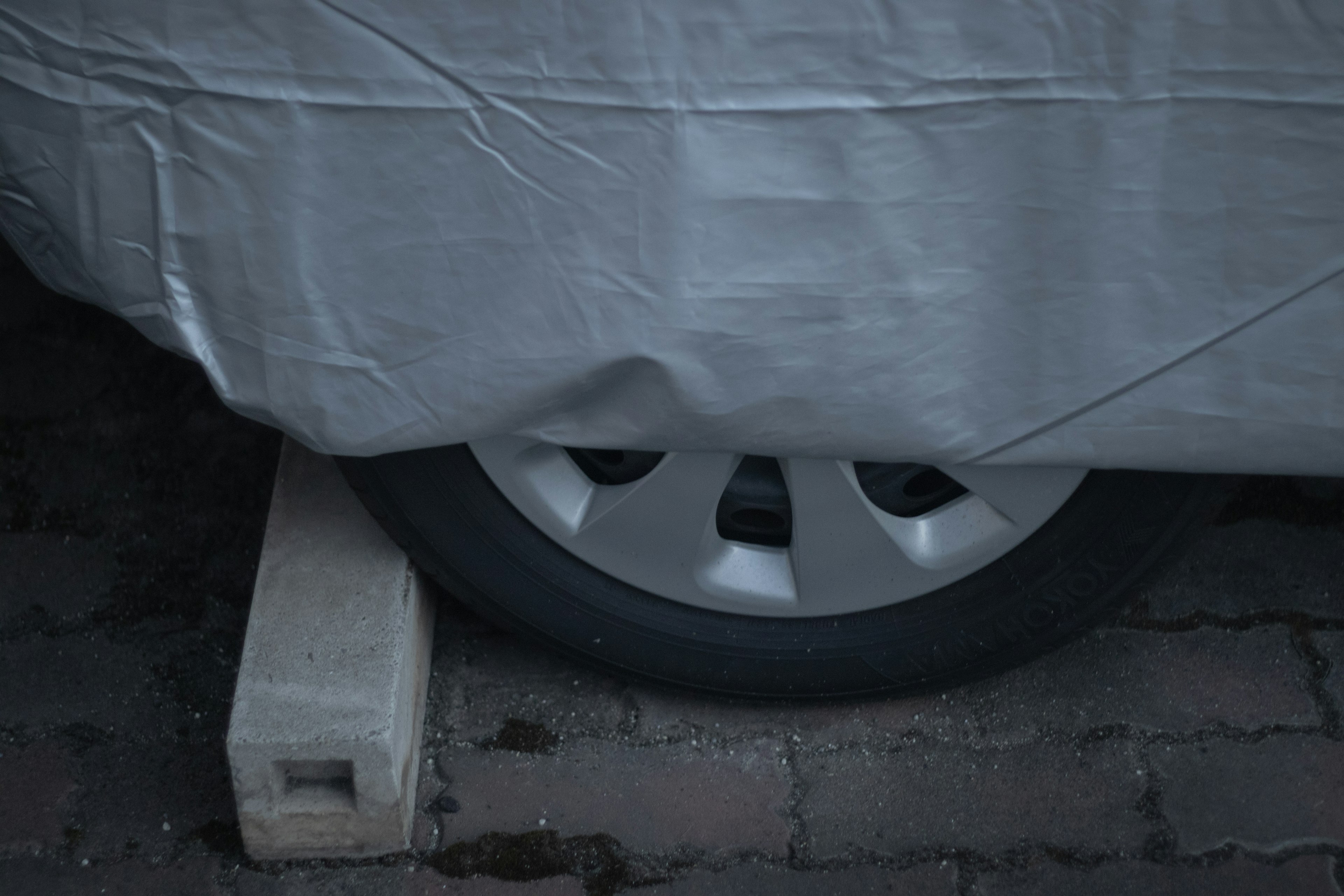 Neumático de coche apoyado sobre un bloque de madera con una cubierta