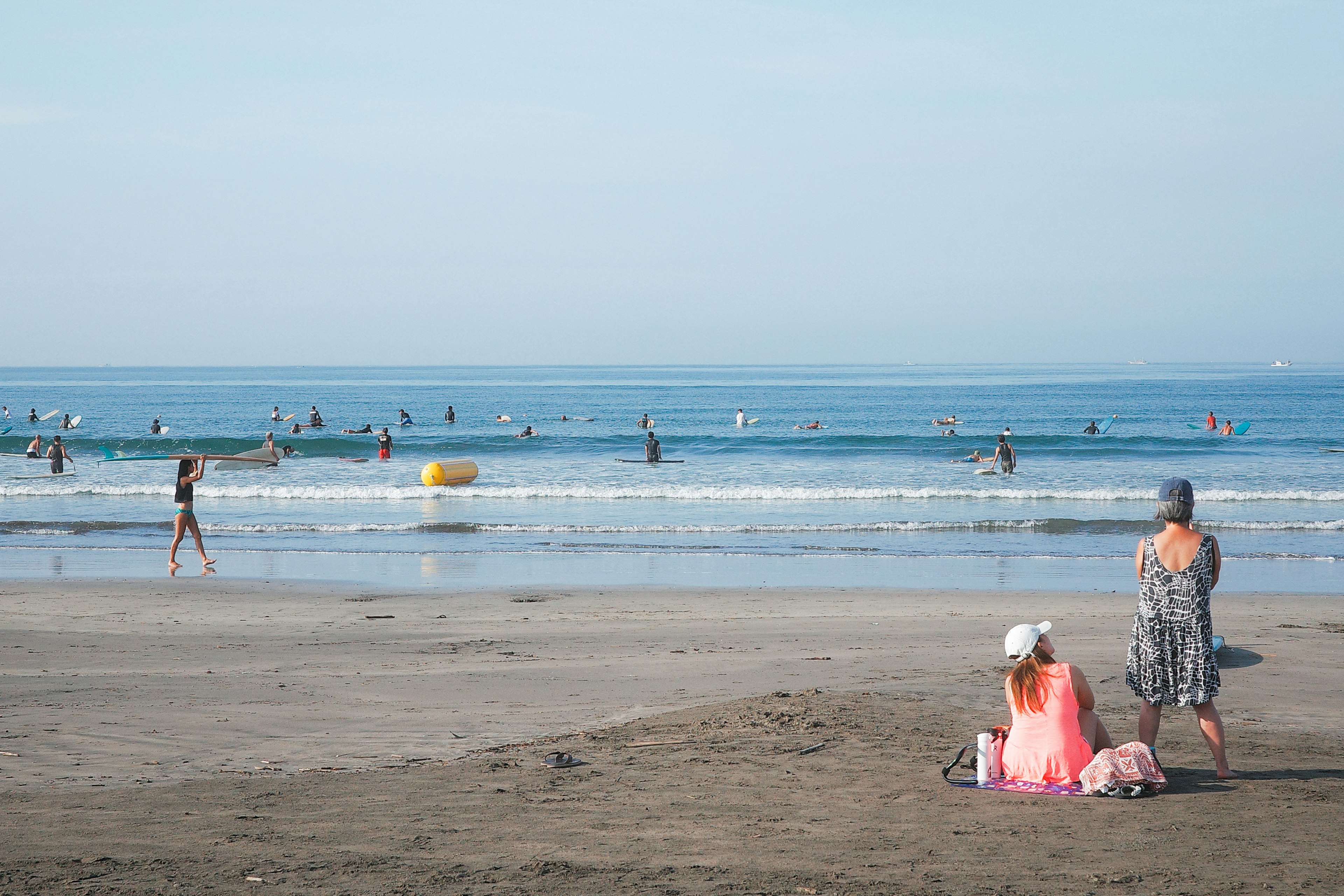 Escena de playa con personas disfrutando de las olas y el océano