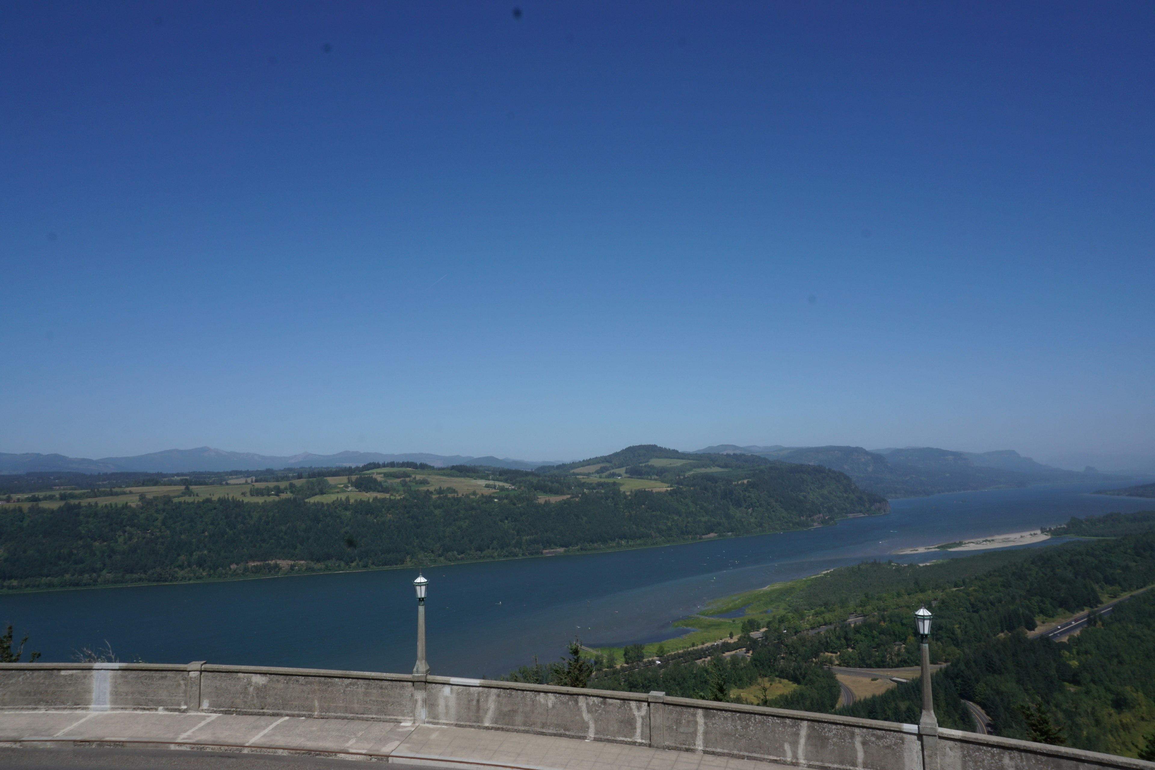 Vue pittoresque de collines verdoyantes sous un ciel bleu clair avec une rivière qui coule