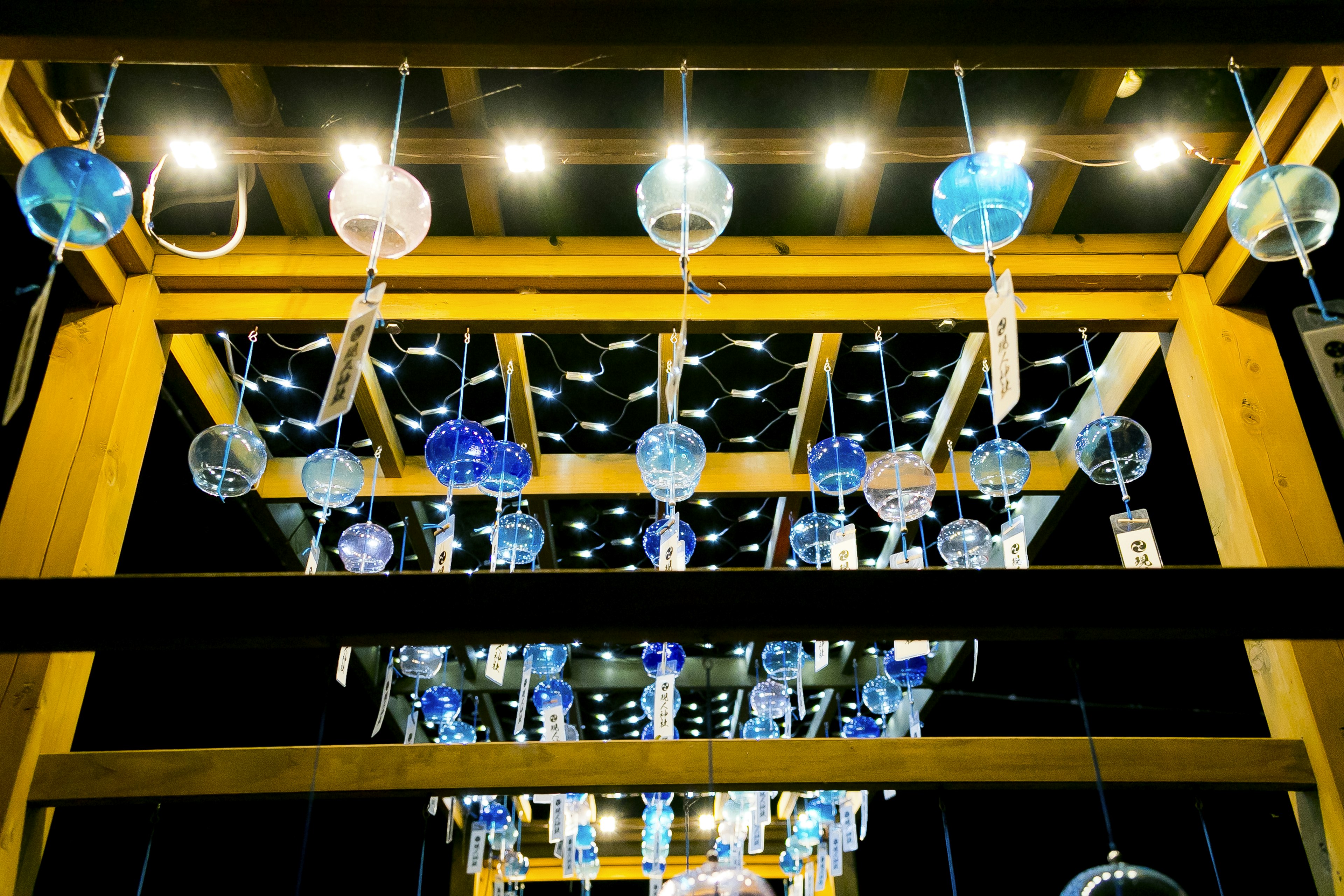 View from below of wooden structure with blue glass wind chimes hanging