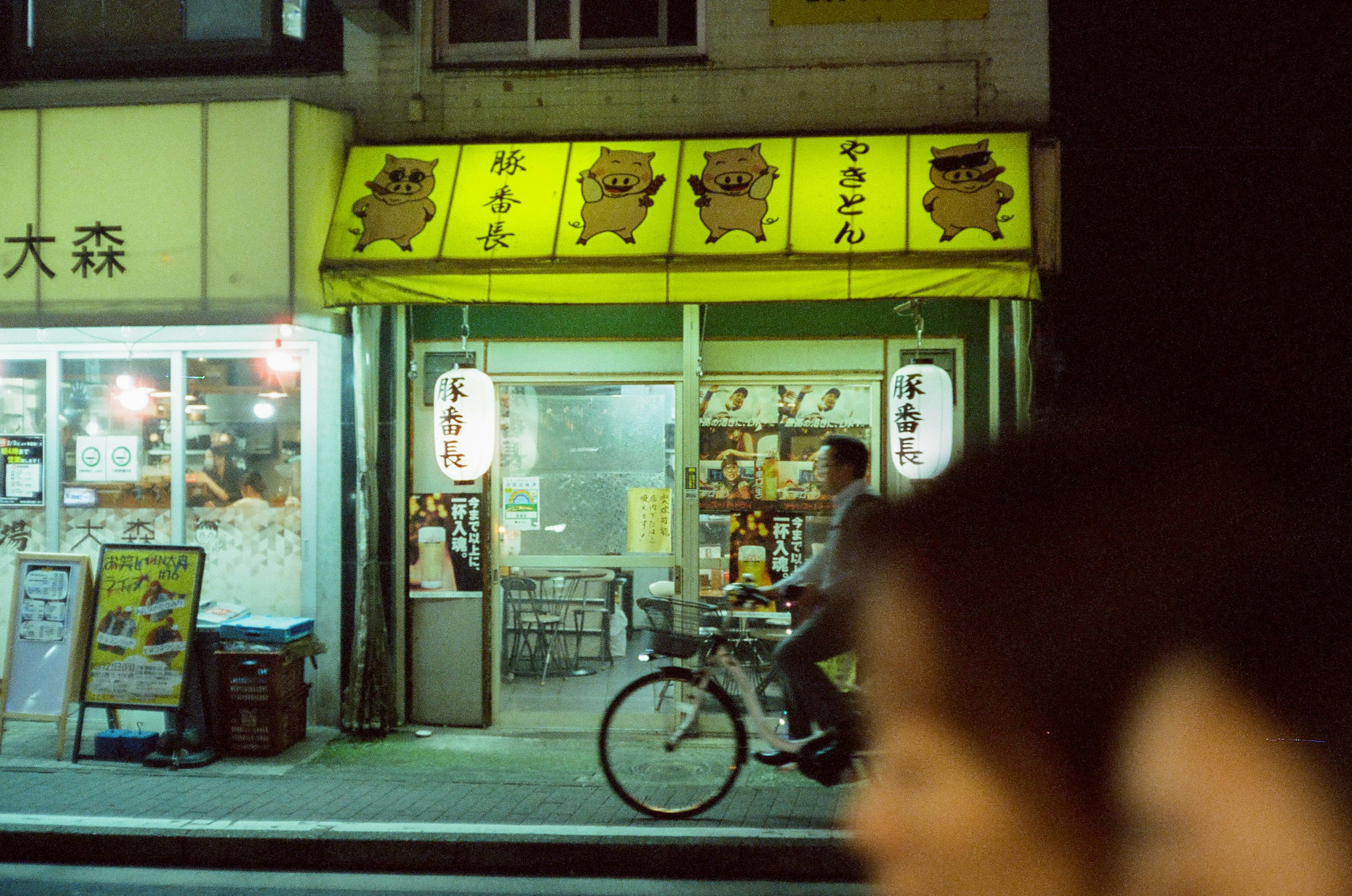 Bright yellow sign of a restaurant at night with a bicycle parked outside