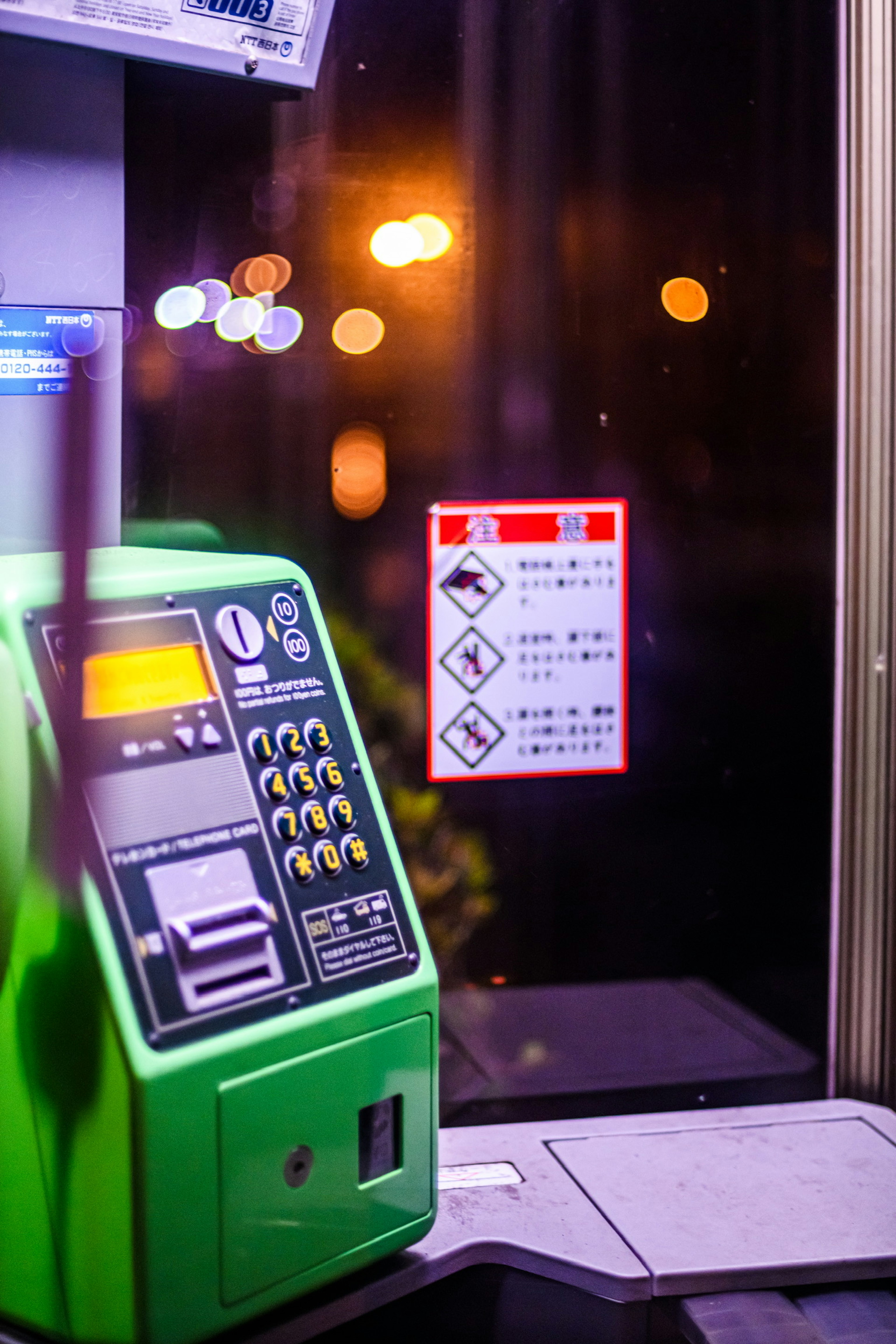 Green vending machine with warning sign against a night backdrop