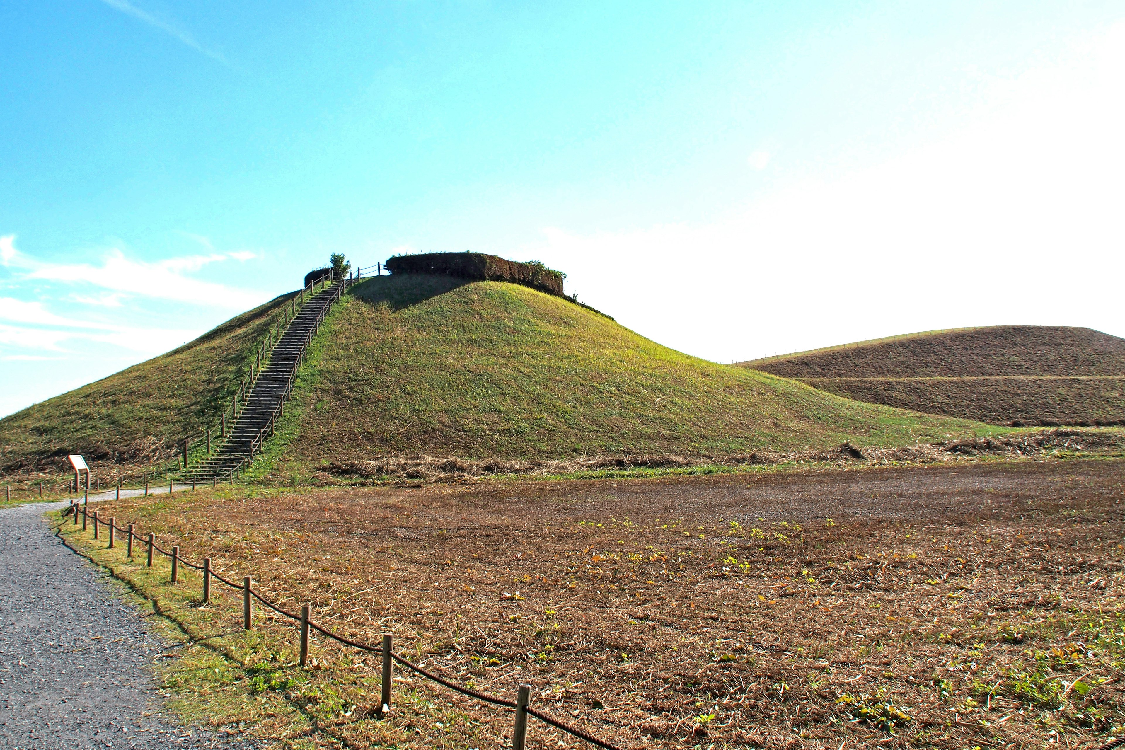 Landschaft mit einem alten Hügel und einer Struktur oben grüne Wiese und blauer Himmel