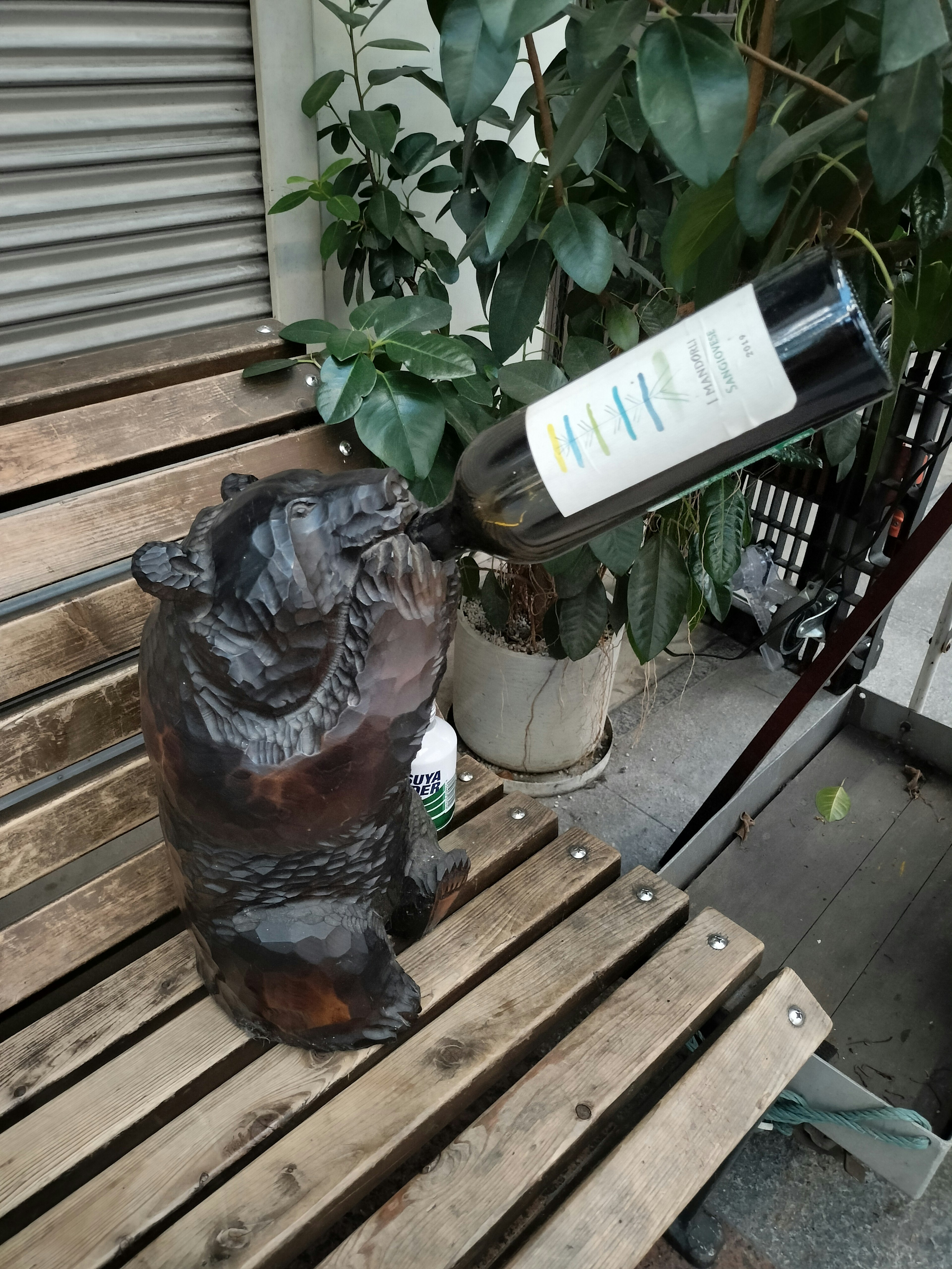 木製熊雕塑 holding a wine bottle