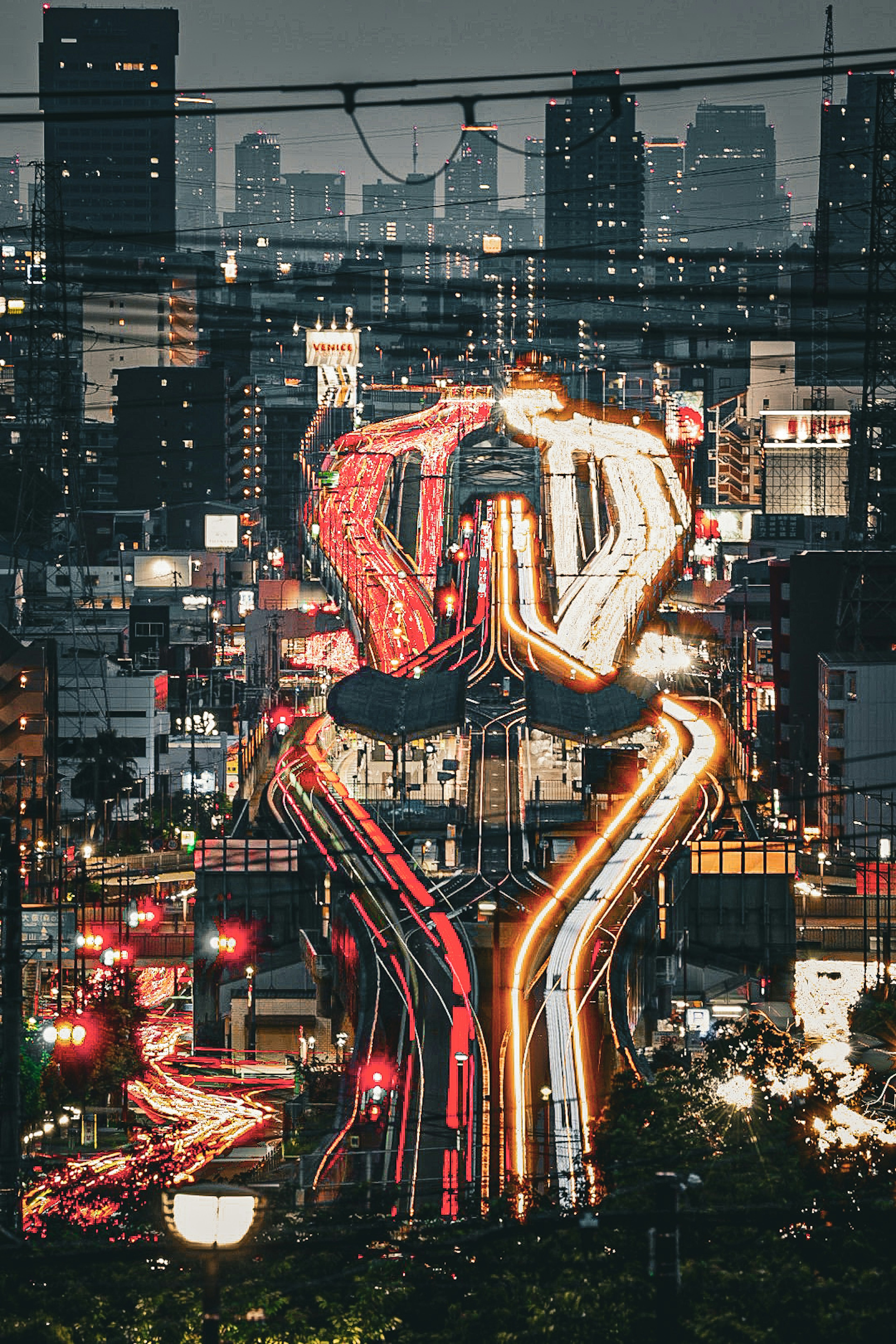 Cityscape at night featuring illuminated traffic flow and skyscrapers