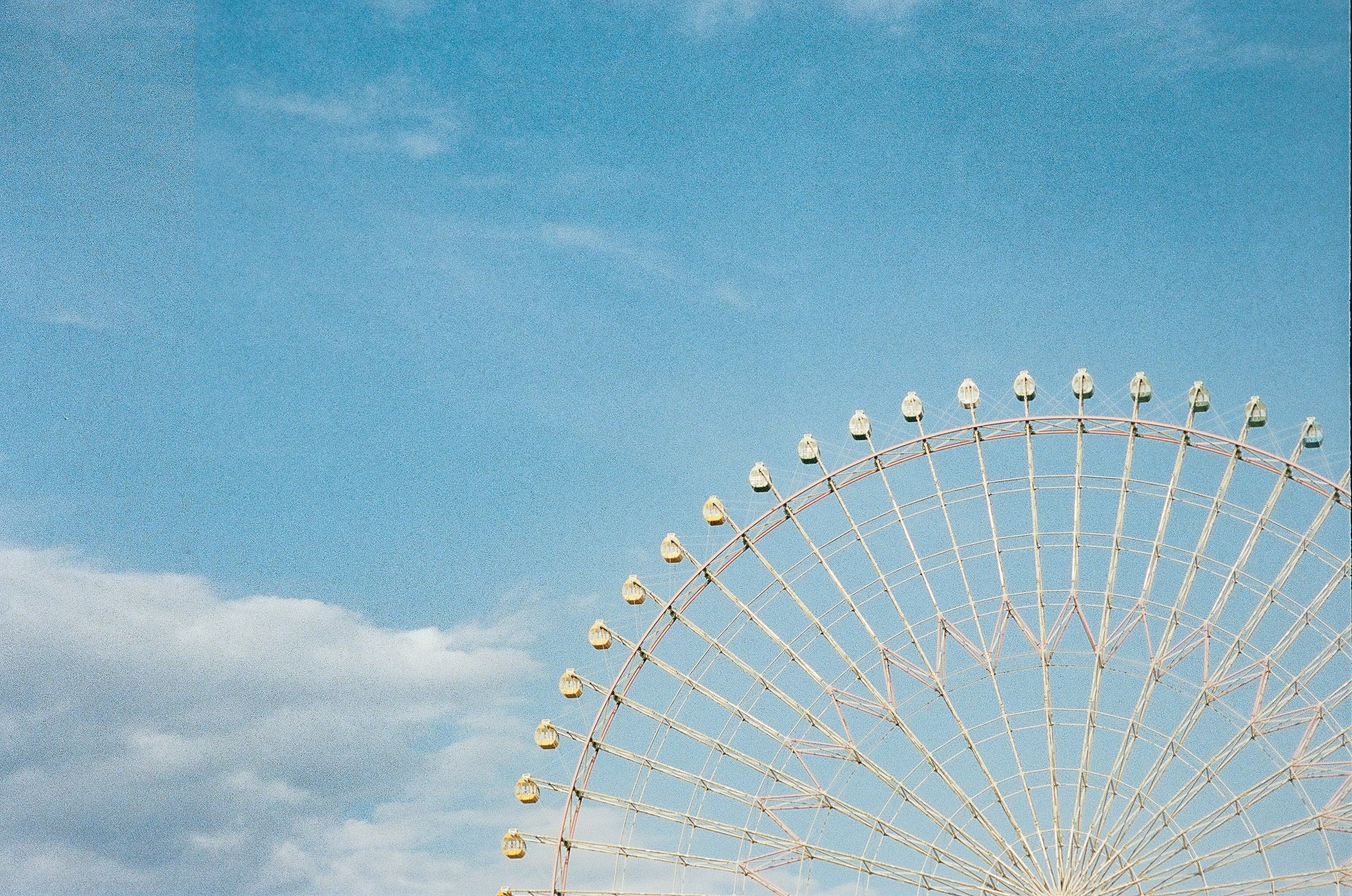 Partial view of a Ferris wheel against a blue sky