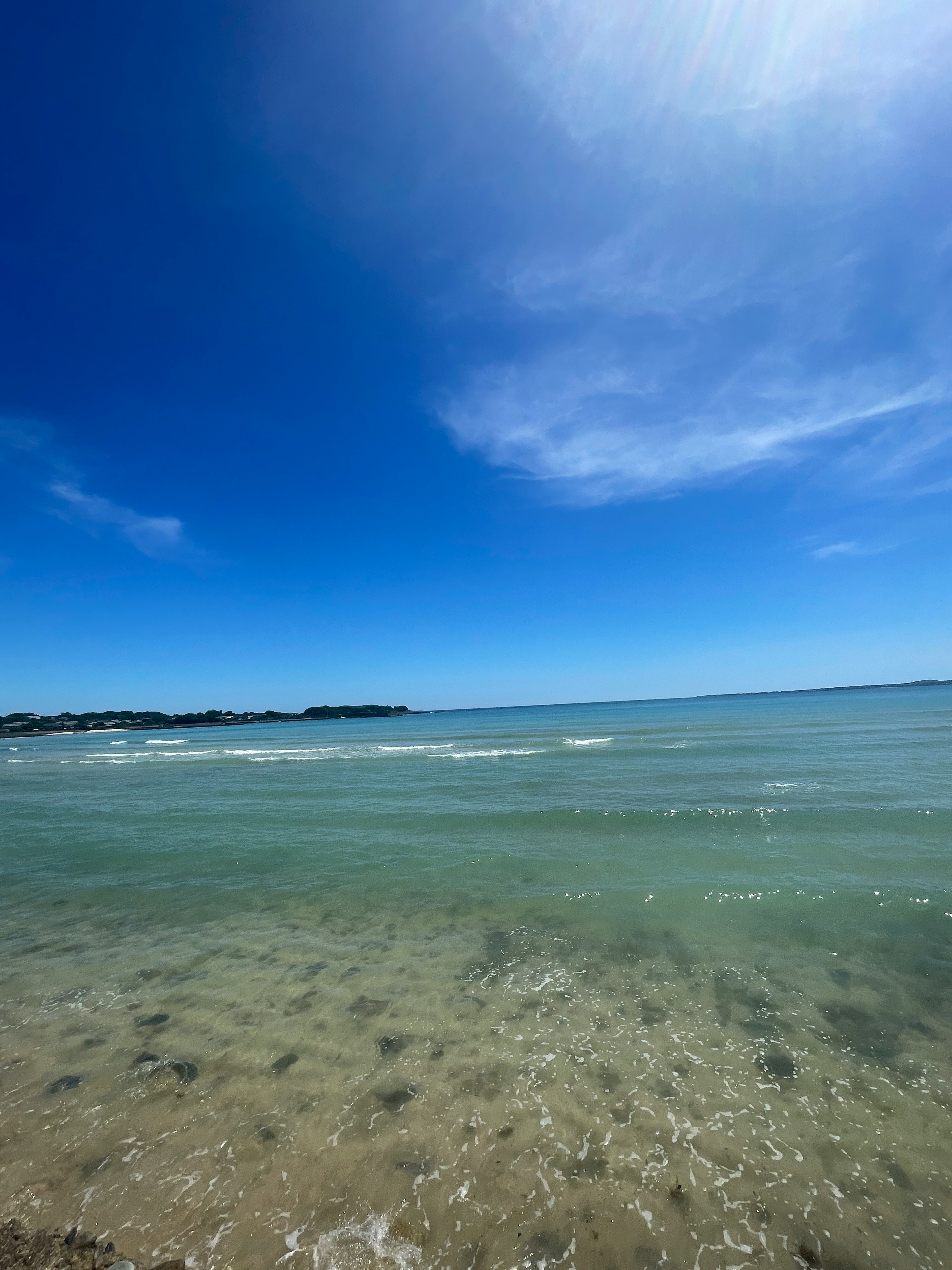 Scenic view of a blue sky and calm sea with clear water and sandy beach