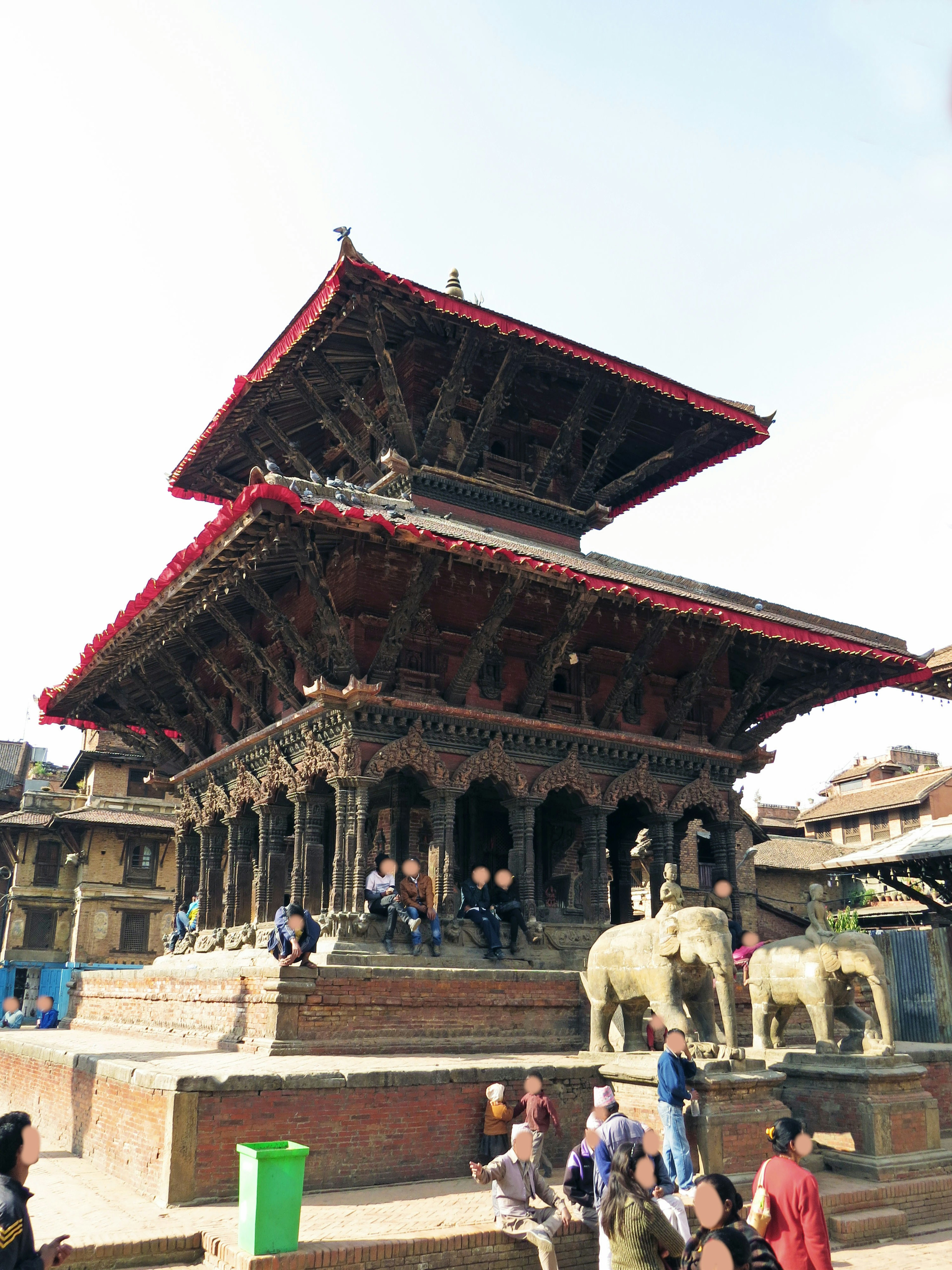 Traditional Nepalese temple with intricate wood carvings red roof people gathered