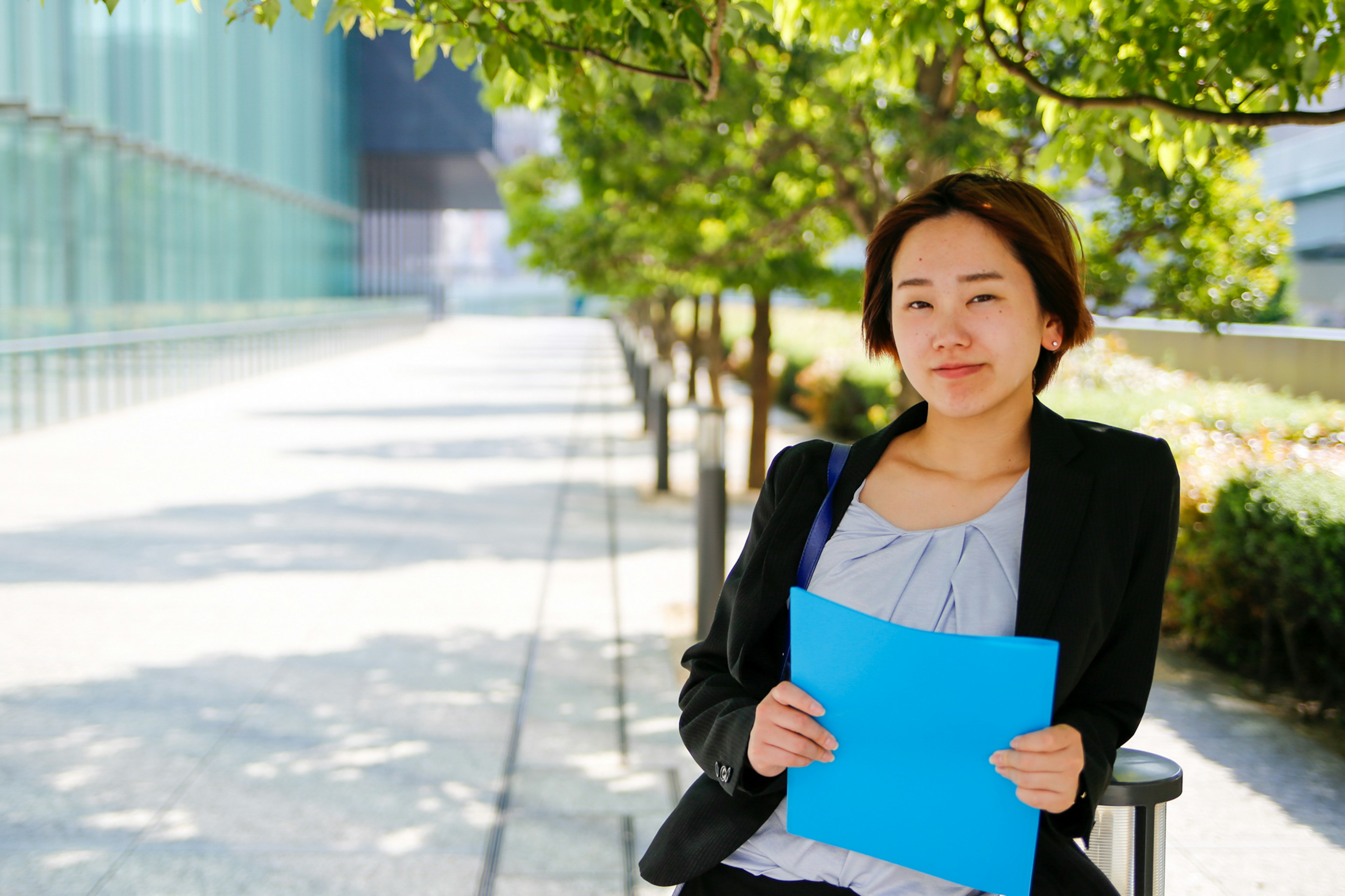 Femme assise tenant un dossier bleu dans un cadre professionnel