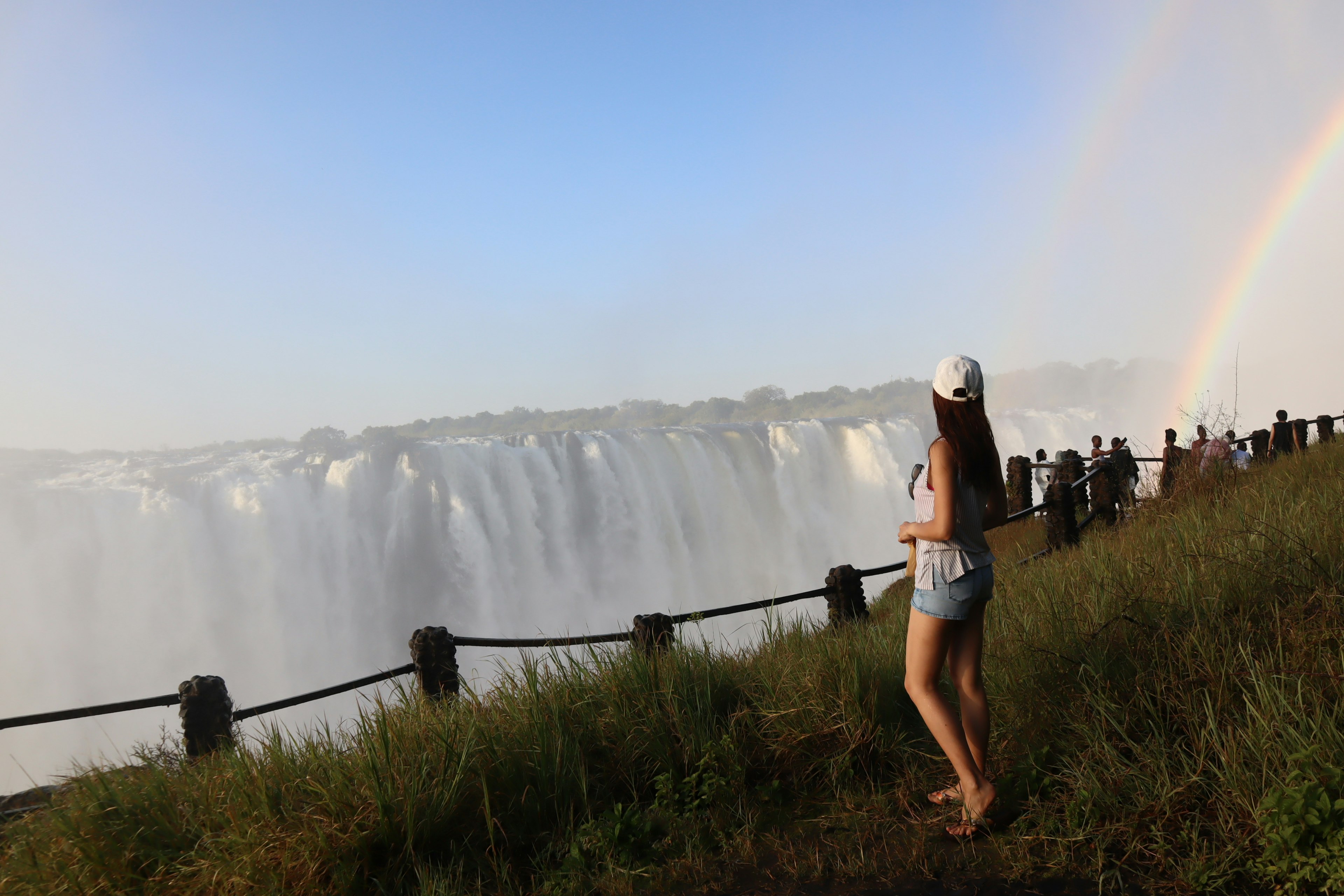 Donna che osserva una cascata con un arcobaleno sullo sfondo