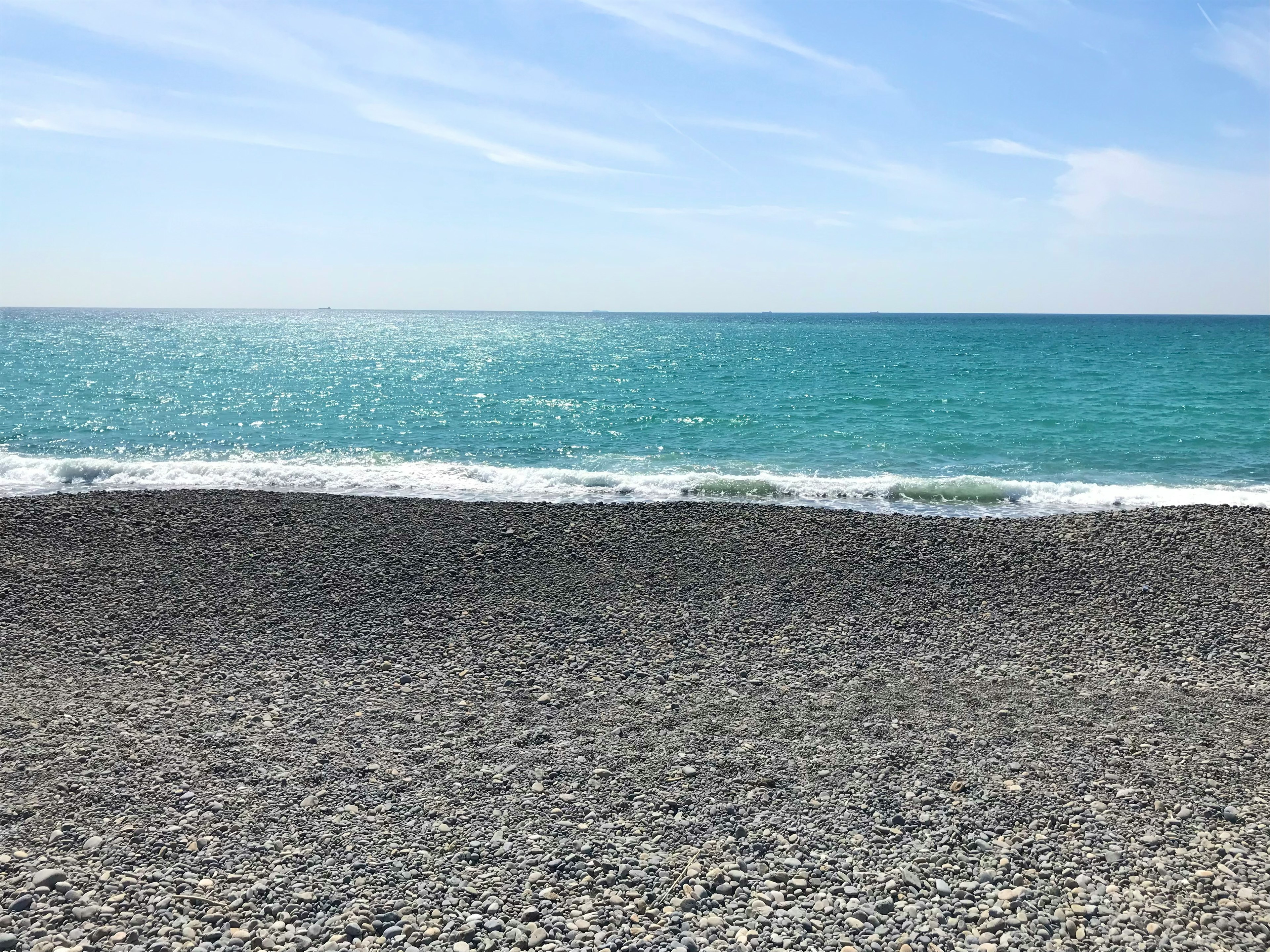 Una playa rocosa con un mar azul claro y olas suaves