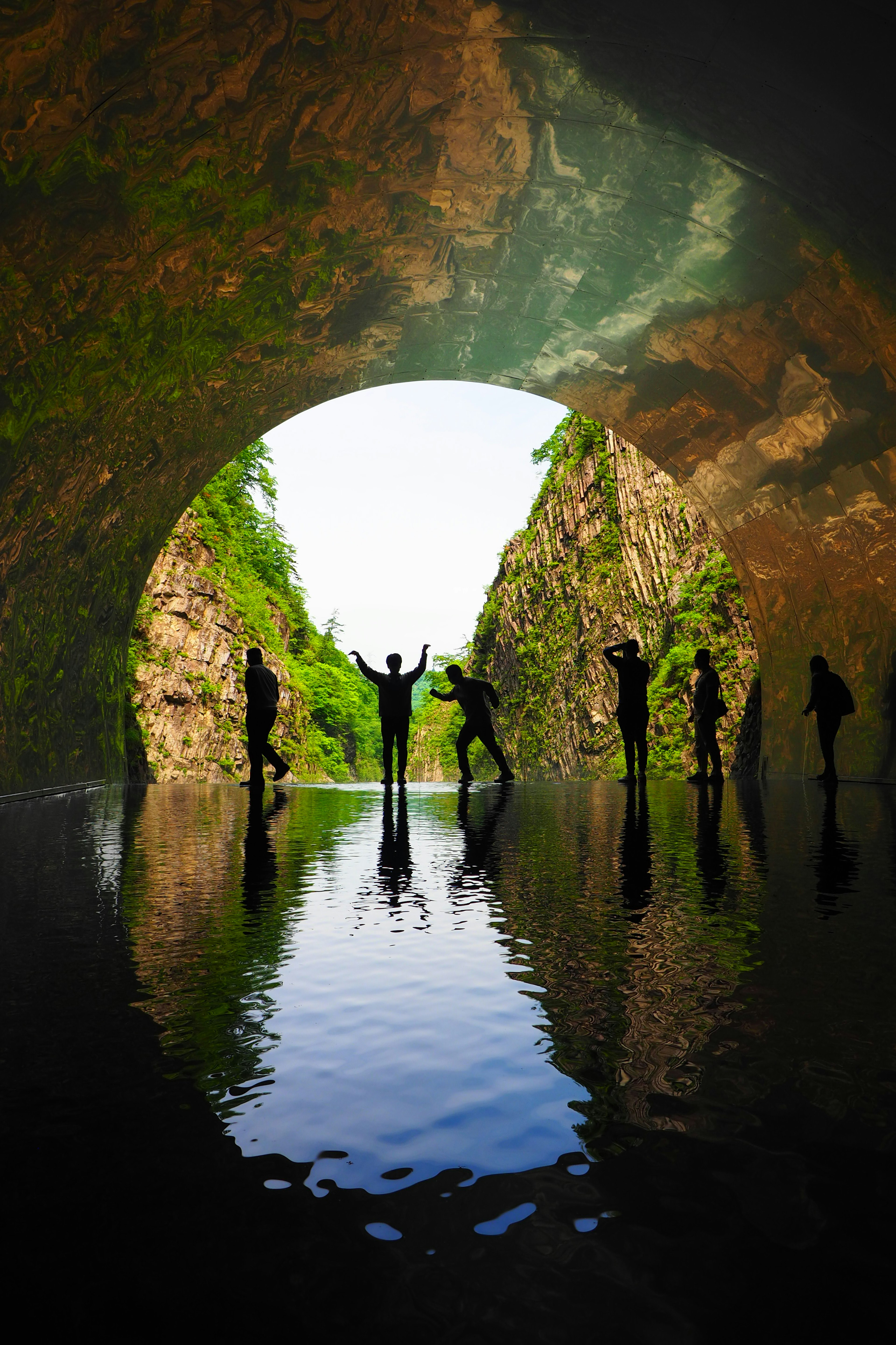 Silhouettes de personnes à l'entrée d'une grotte avec des reflets sur l'eau