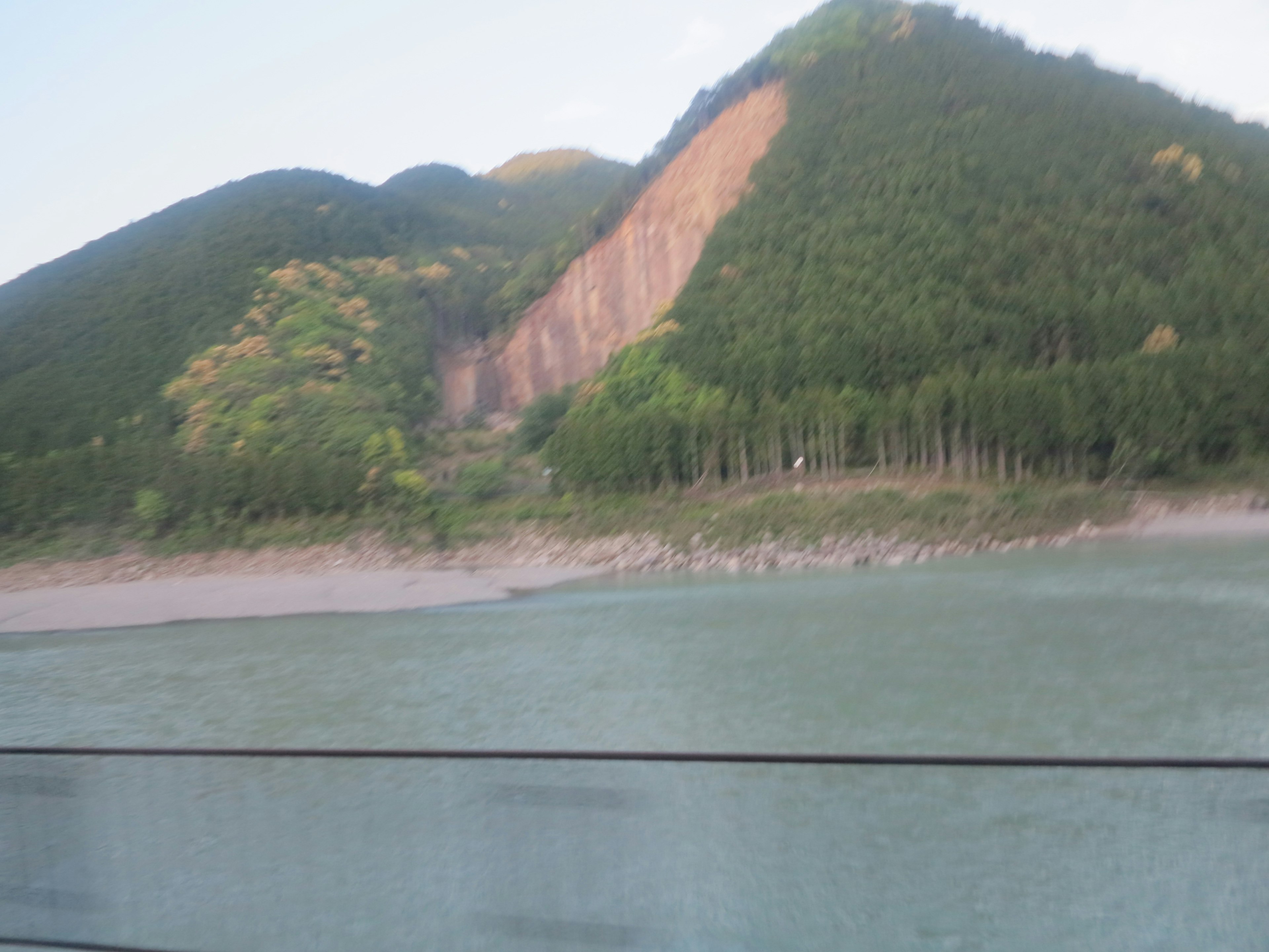 Paysage de montagnes verdoyantes et de rivière avec glissement de terrain visible sur la pente