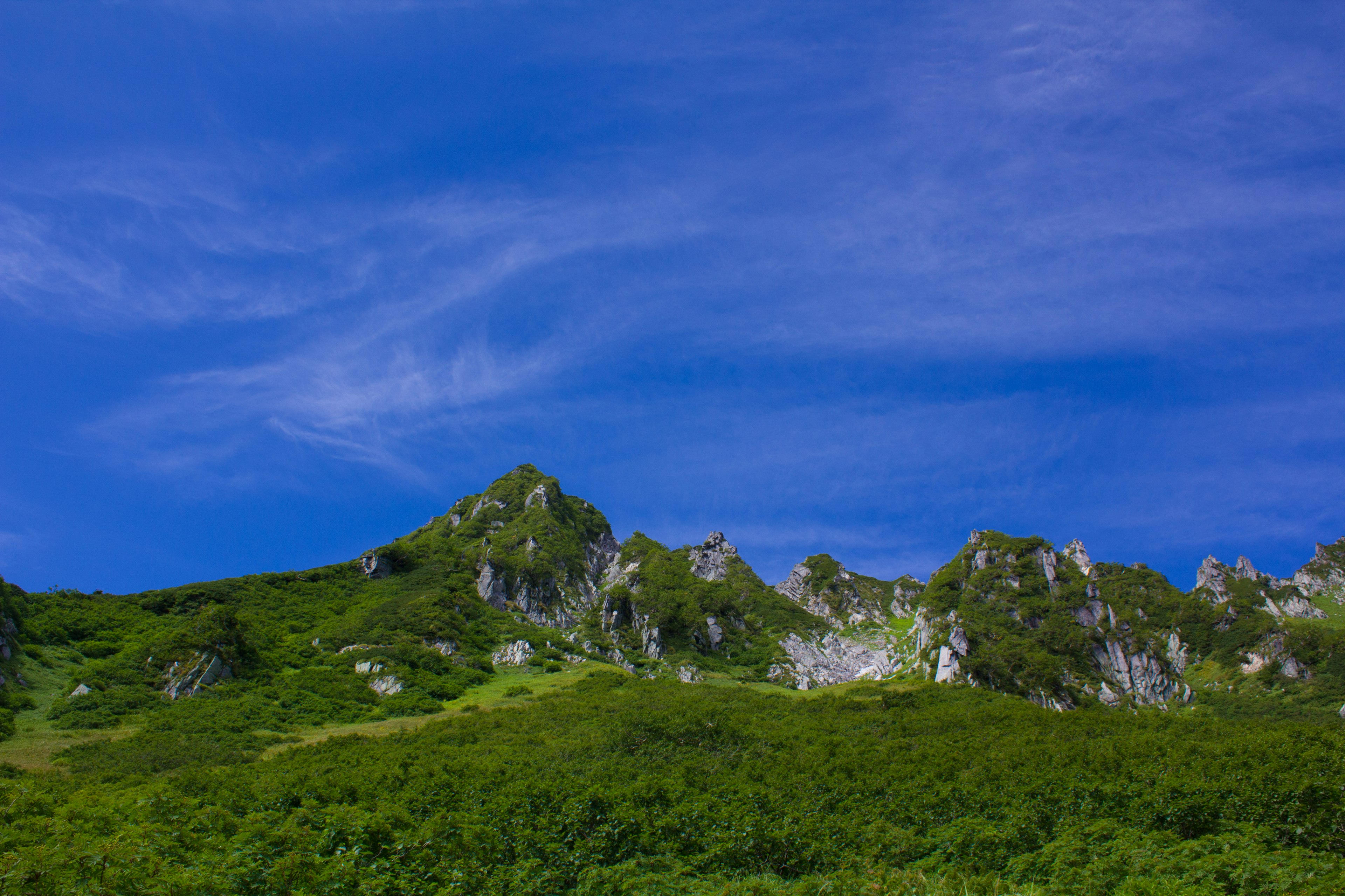 蓝天和绿色丘陵的风景，散落着岩石