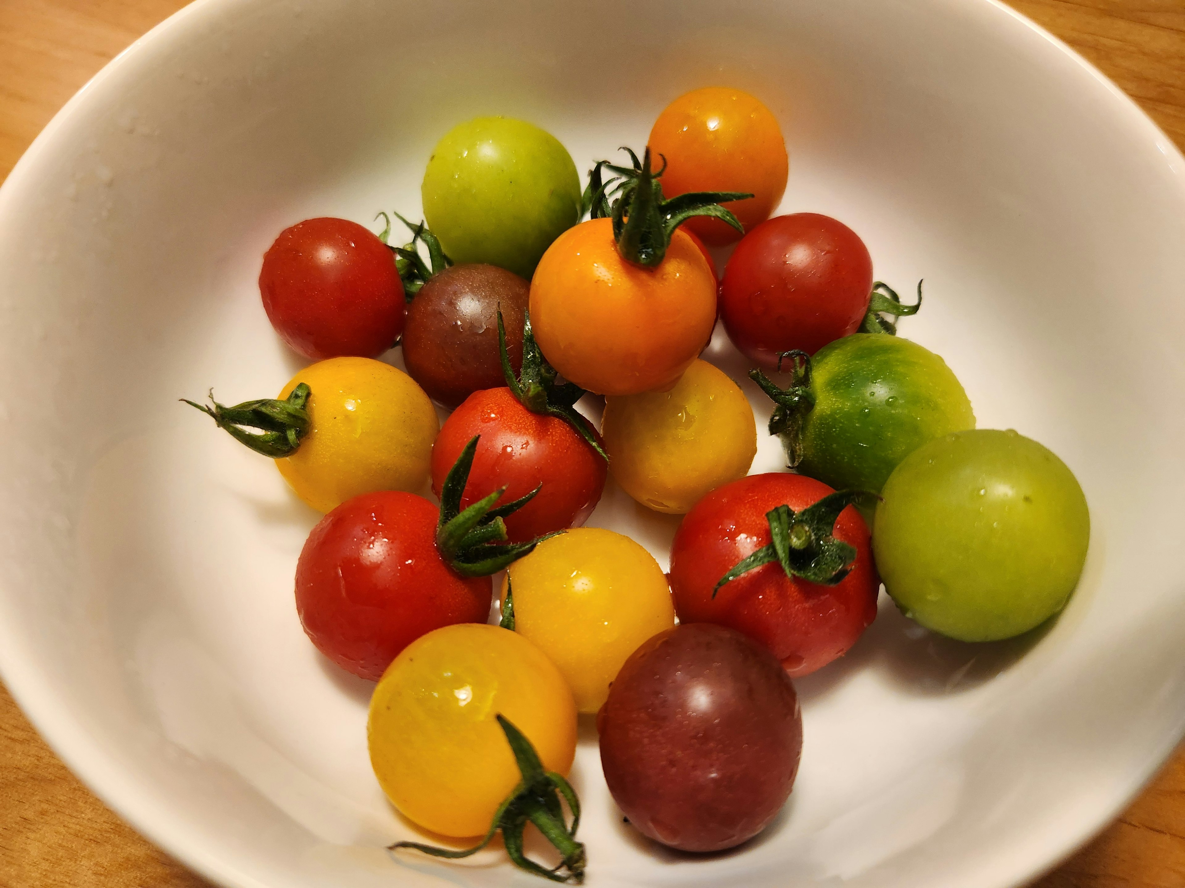 A colorful assortment of cherry tomatoes in a white bowl