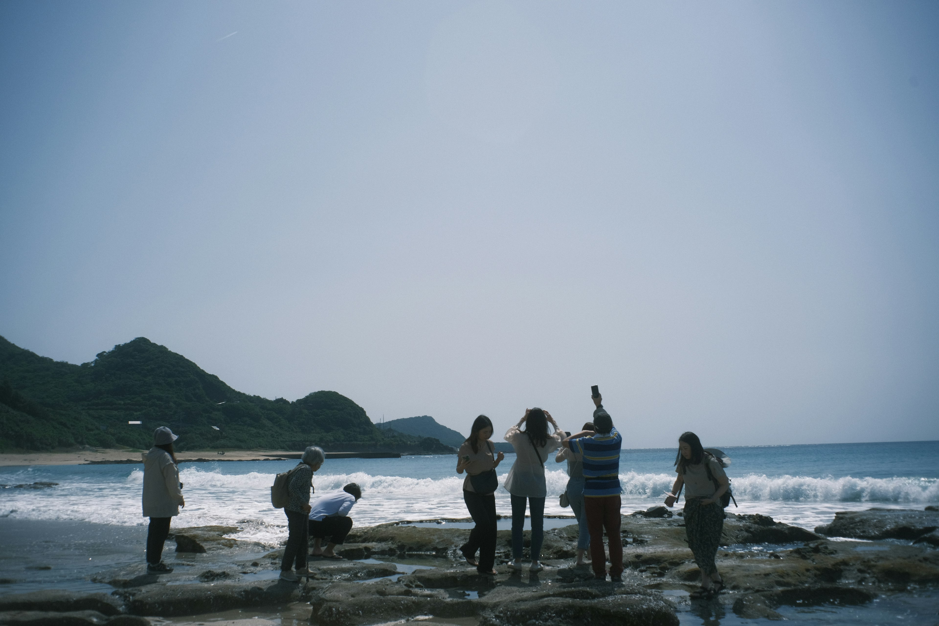 一群人探索岩石海灘與海洋波浪