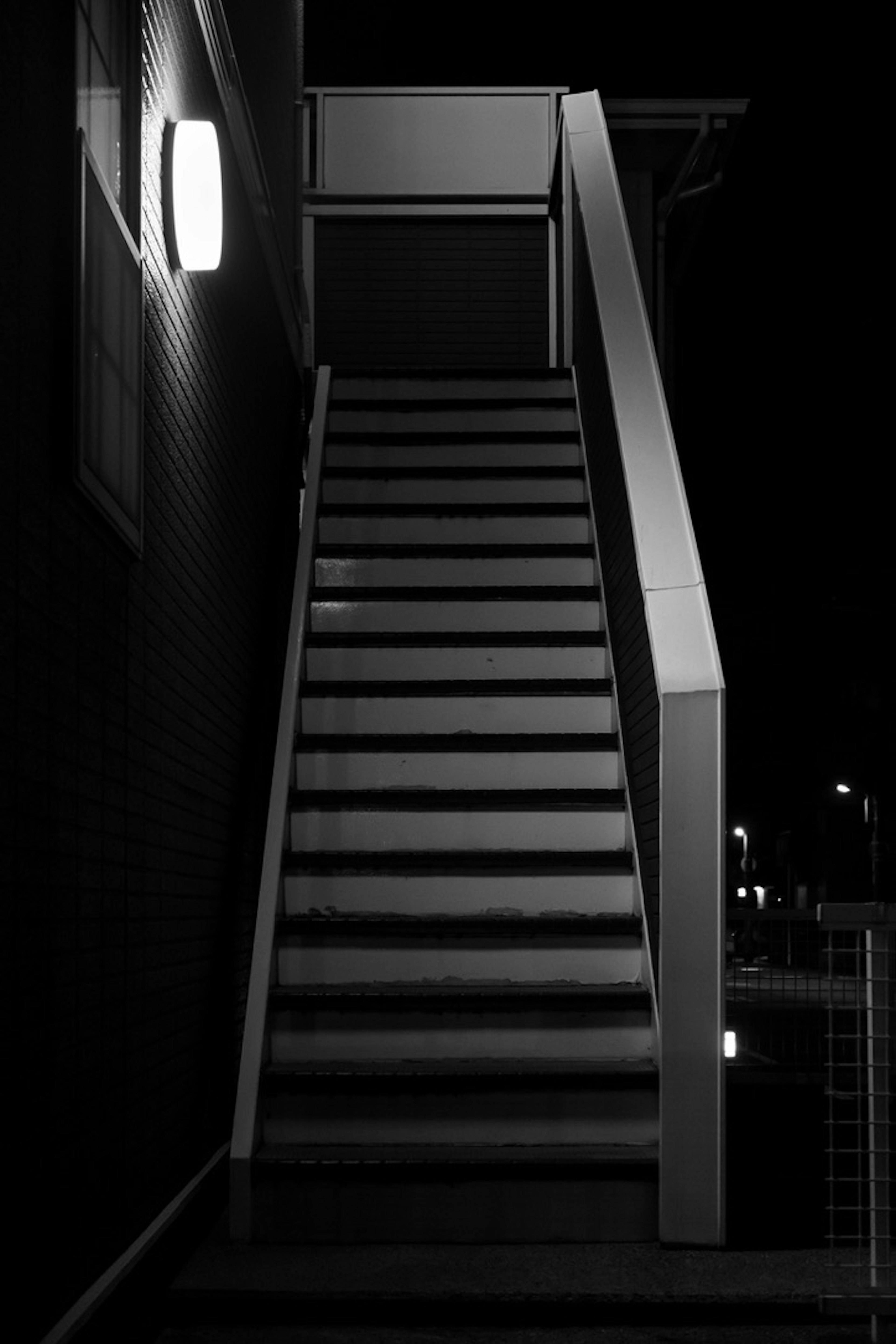 Simple scene of a staircase with wall light at night