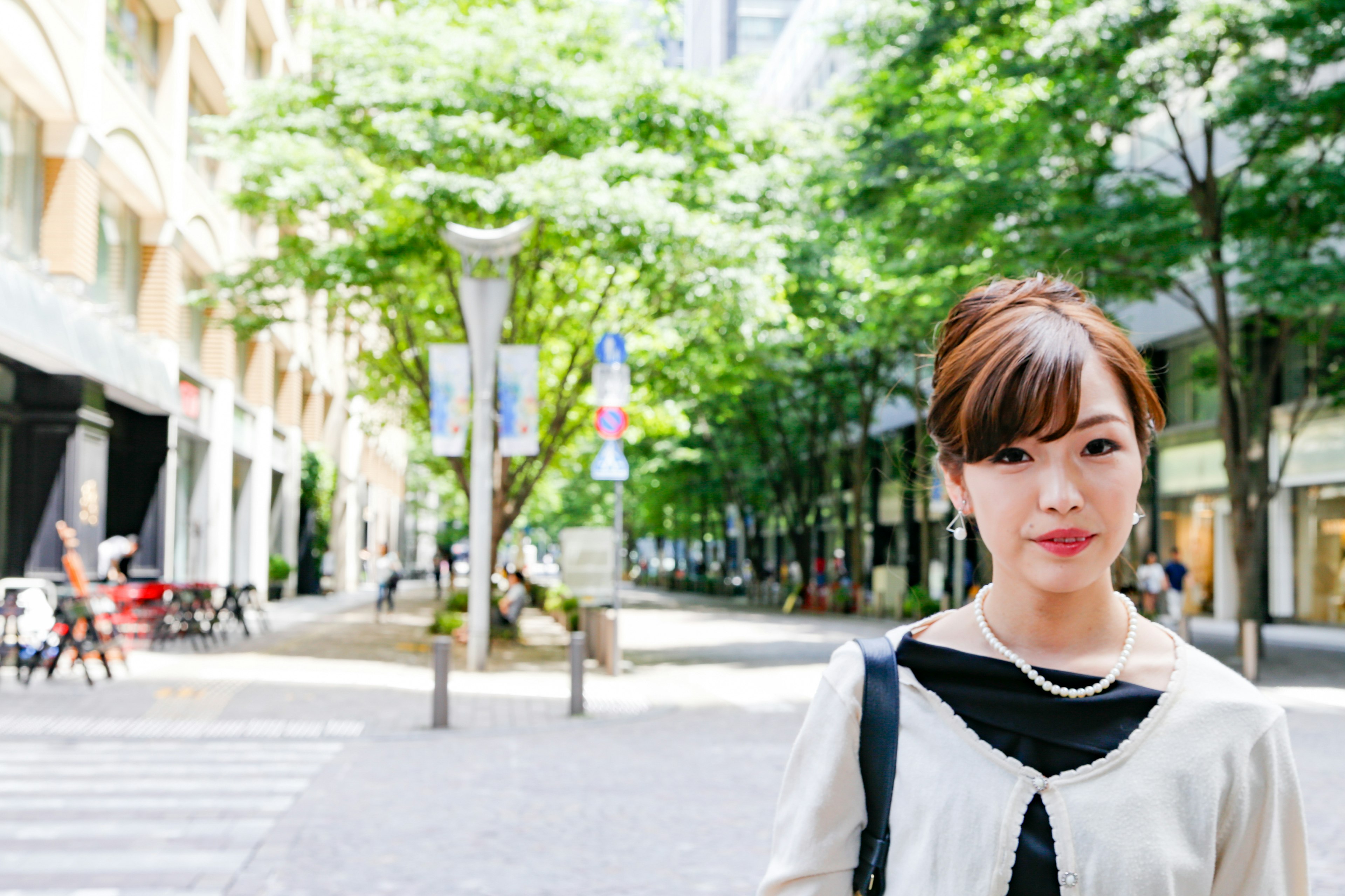 Portrait d'une femme souriante dans une rue de la ville entourée d'arbres verts