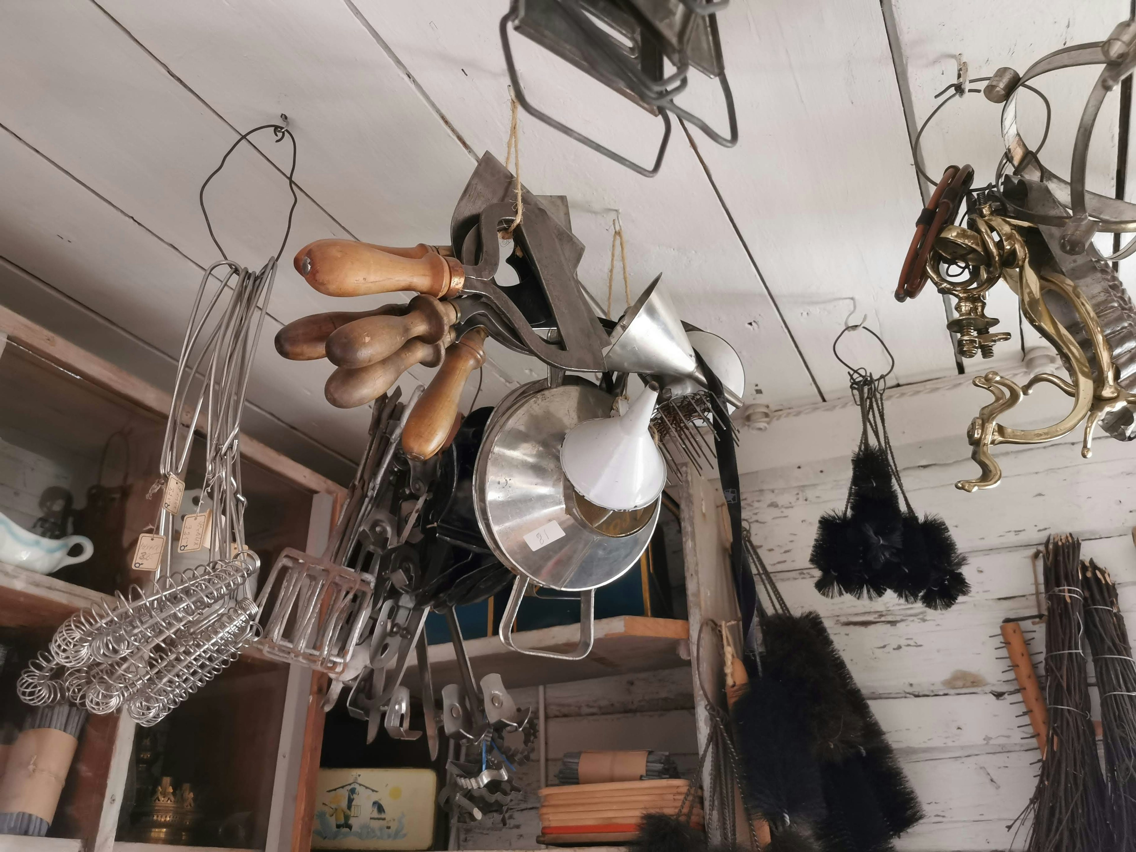 A collection of vintage kitchen utensils hanging from the ceiling