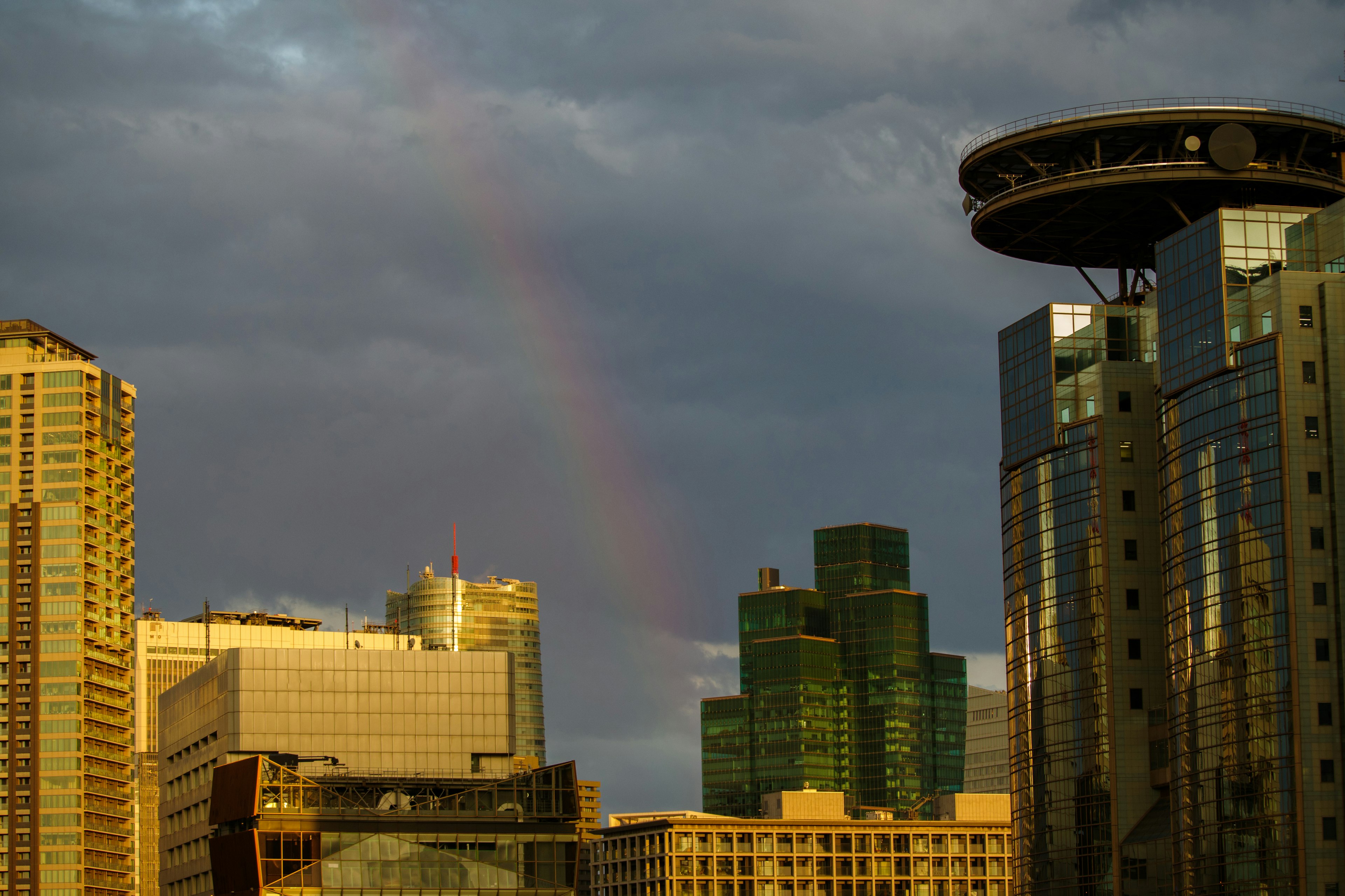 Cityscape with a rainbow above buildings and cloudy sky