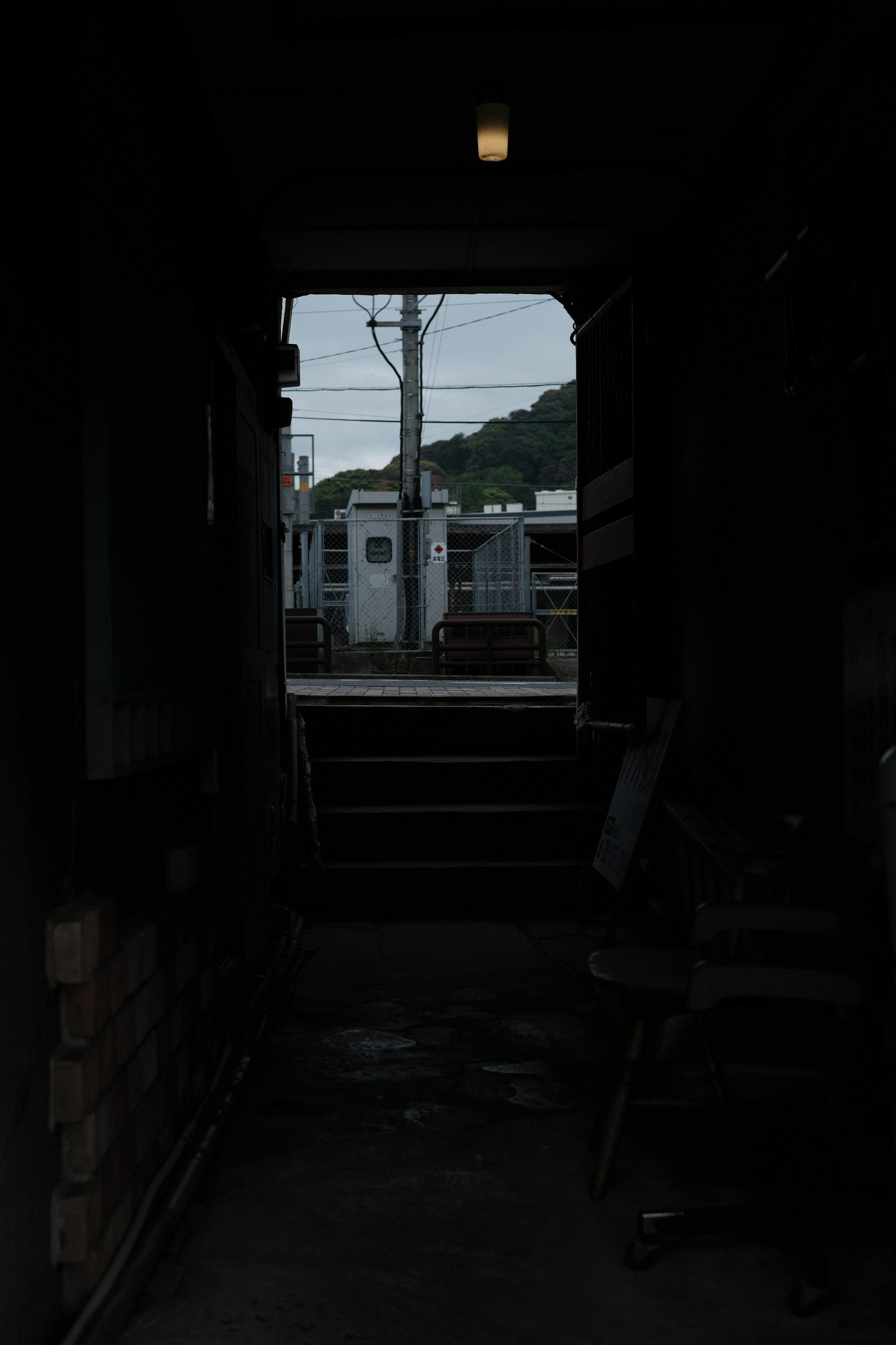 View from a dark corridor showing railway cars and power lines outside