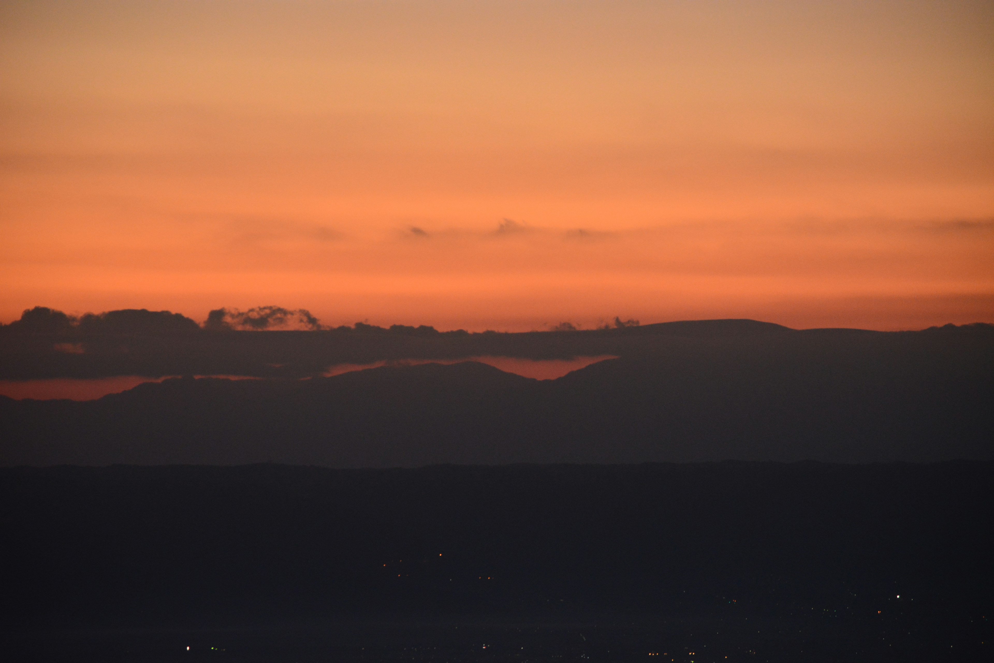 Orangefarbener Sonnenuntergangshimmel mit Silhouetten von Bergen