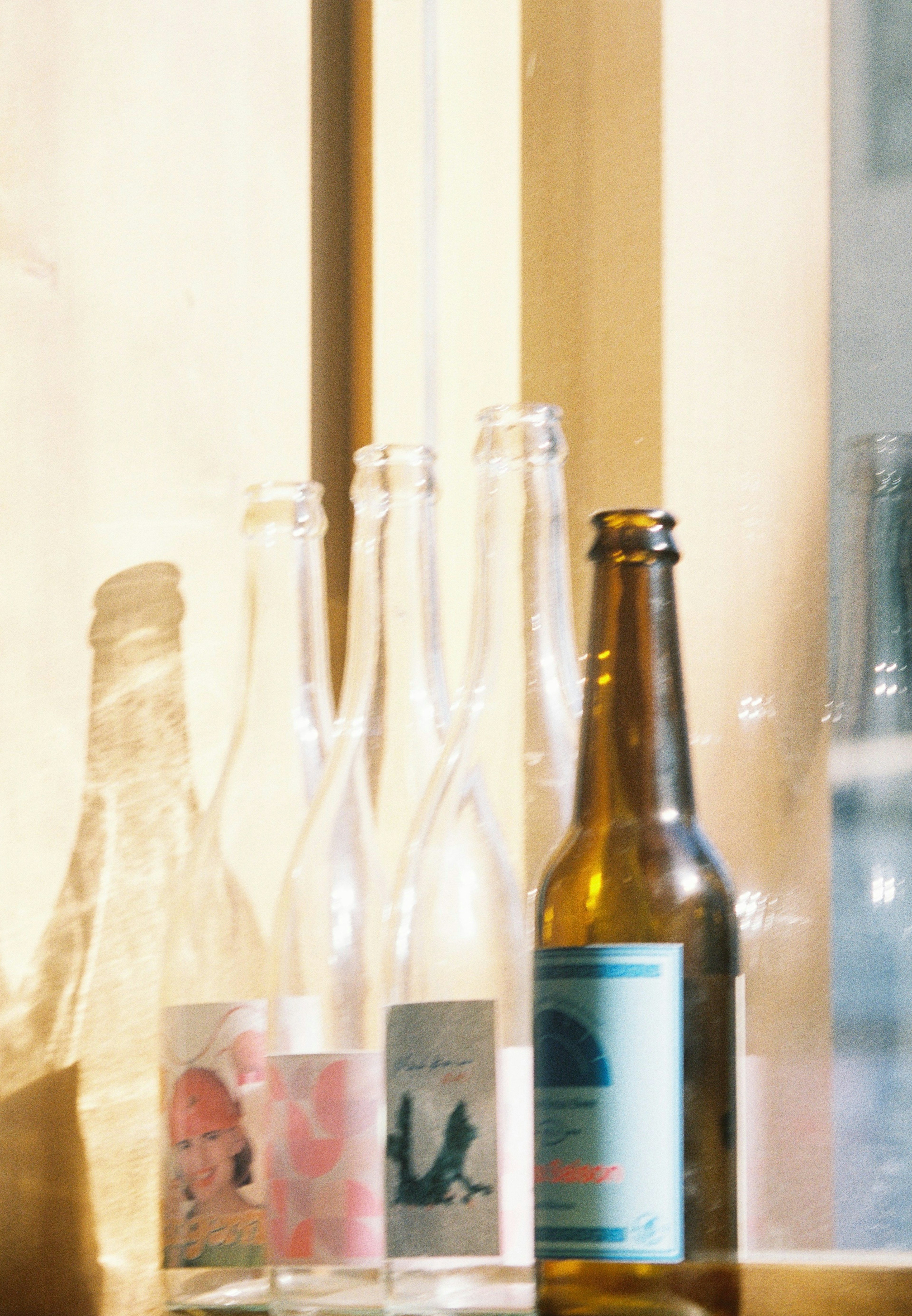 A collection of glass bottles with decorative labels on a windowsill