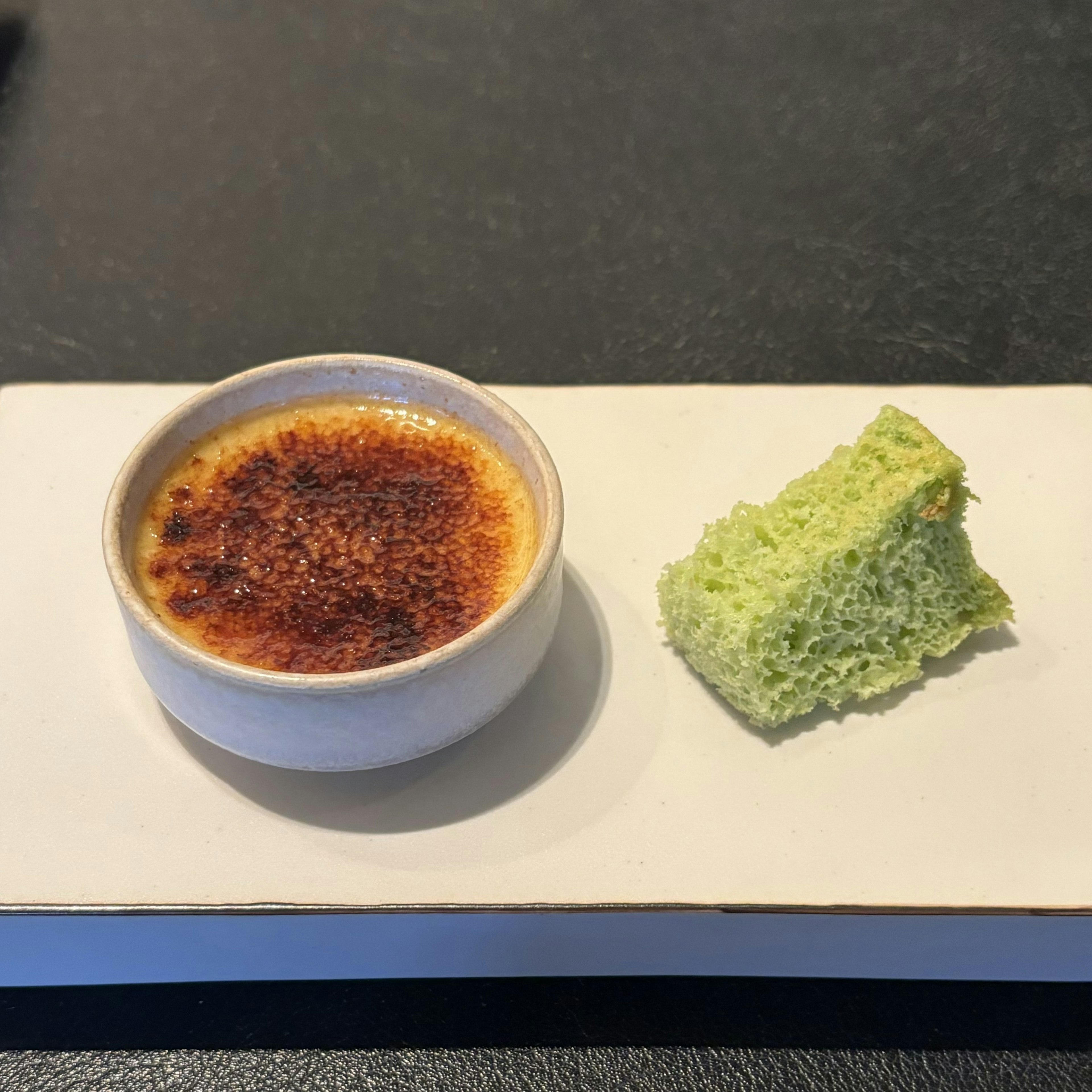 Crème brûlée servie avec un morceau de pain vert