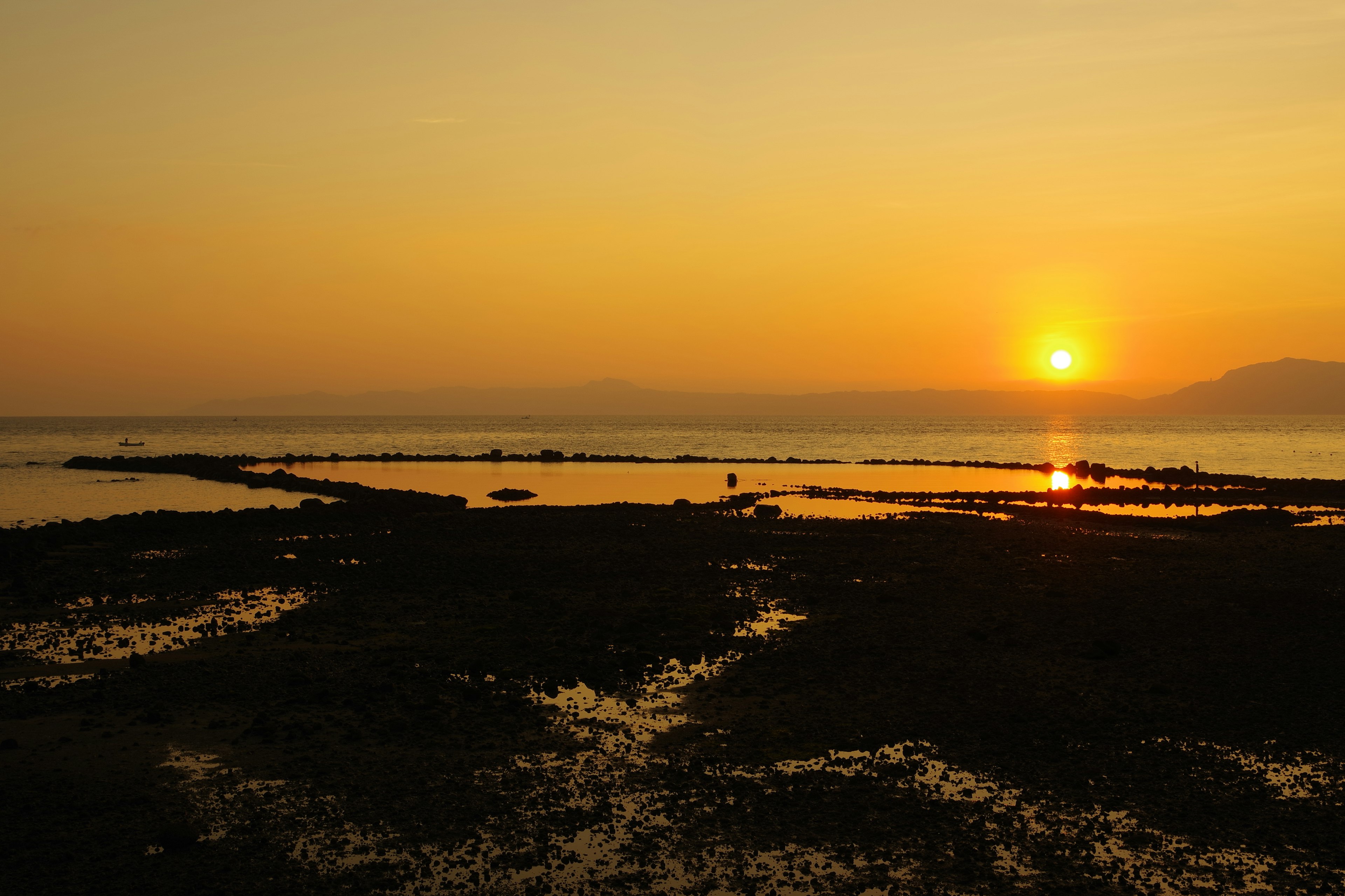 夕日が水平線に沈む海岸の風景