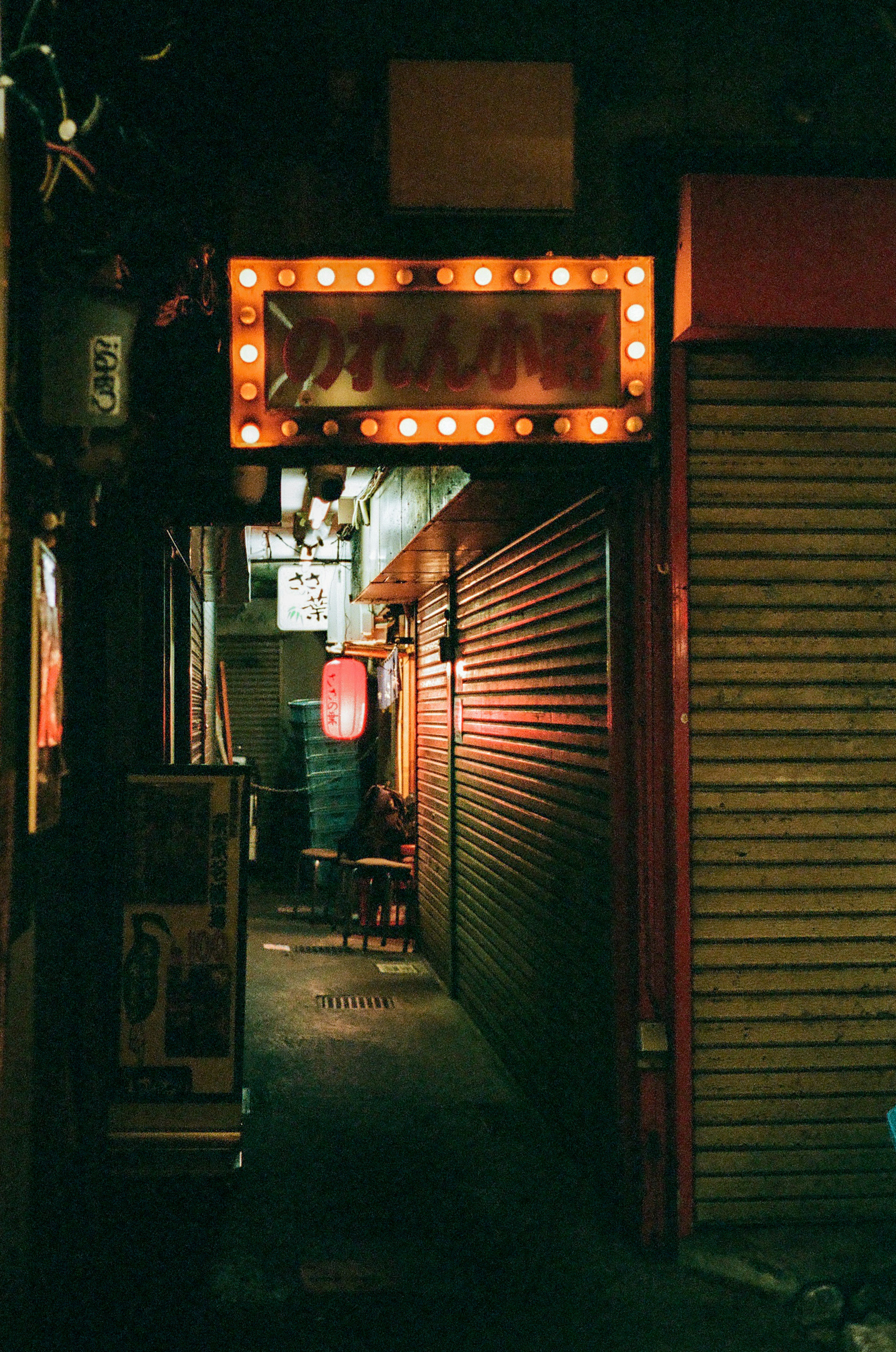 薄暗い路地にあるネオンの看板とシャッター