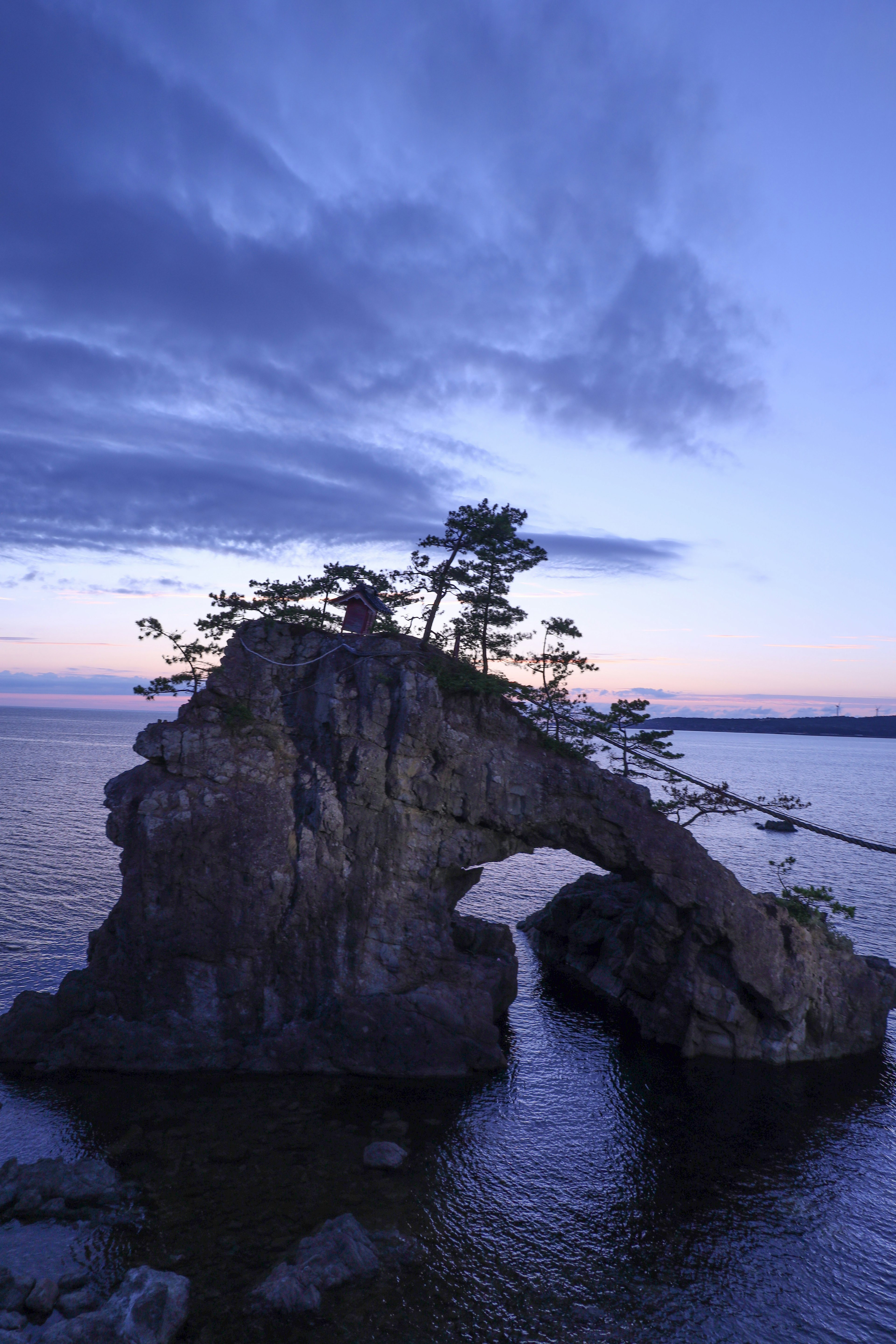 青い空と海に浮かぶ自然の岩のアーチと木々