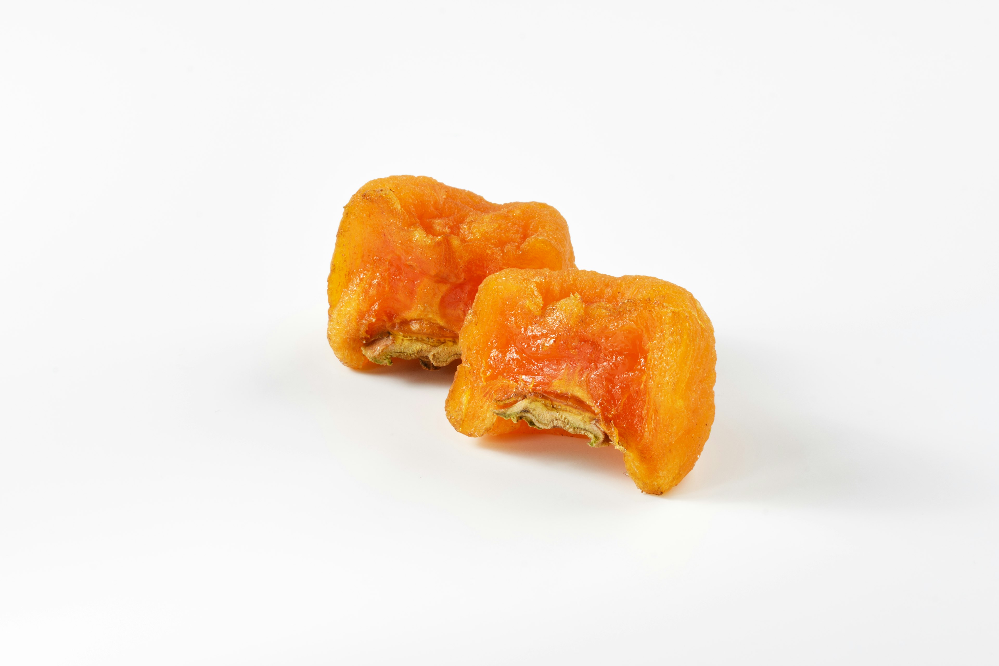 Two orange sweets placed on a white background