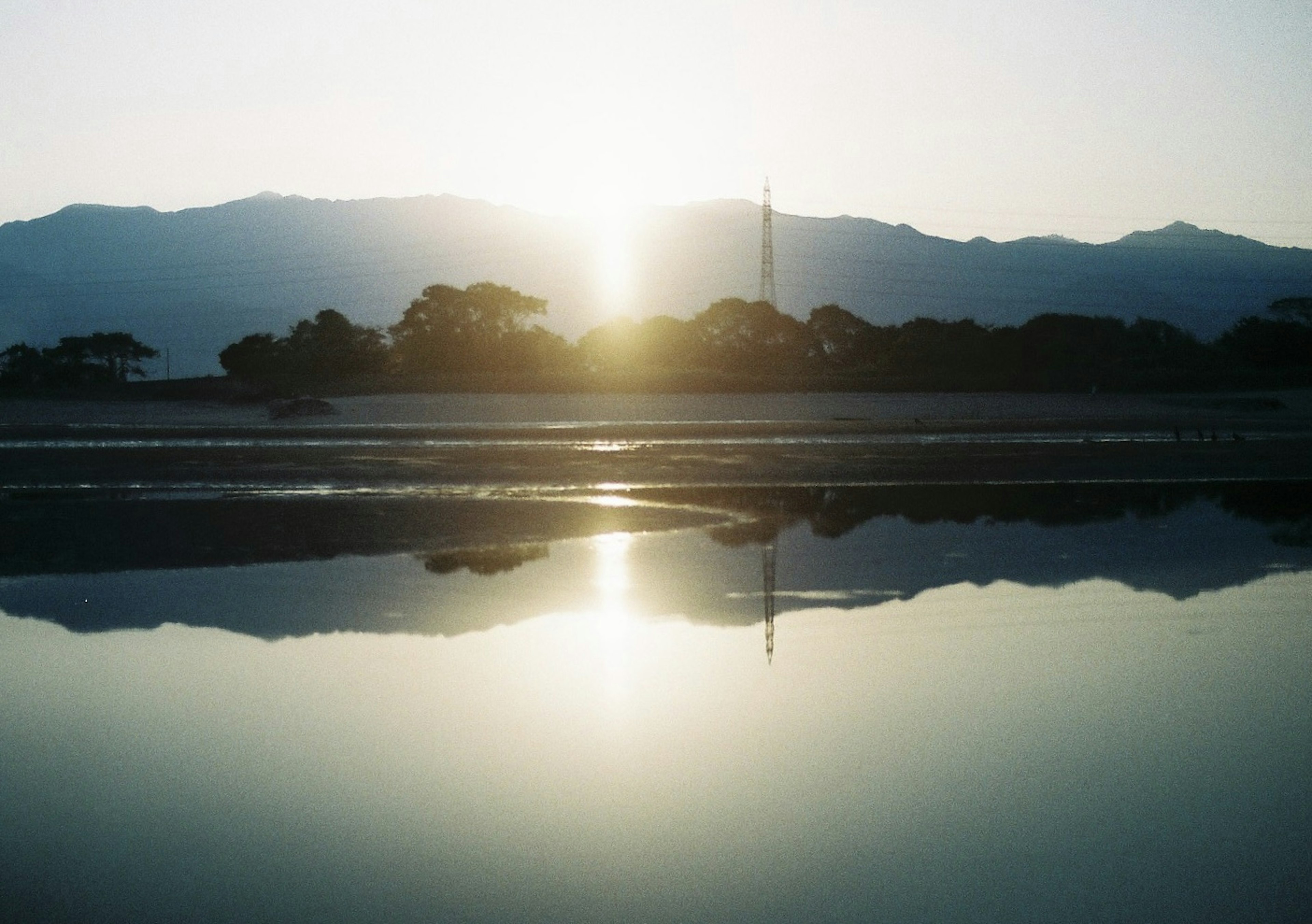 Calm lake reflecting mountains and sunrise