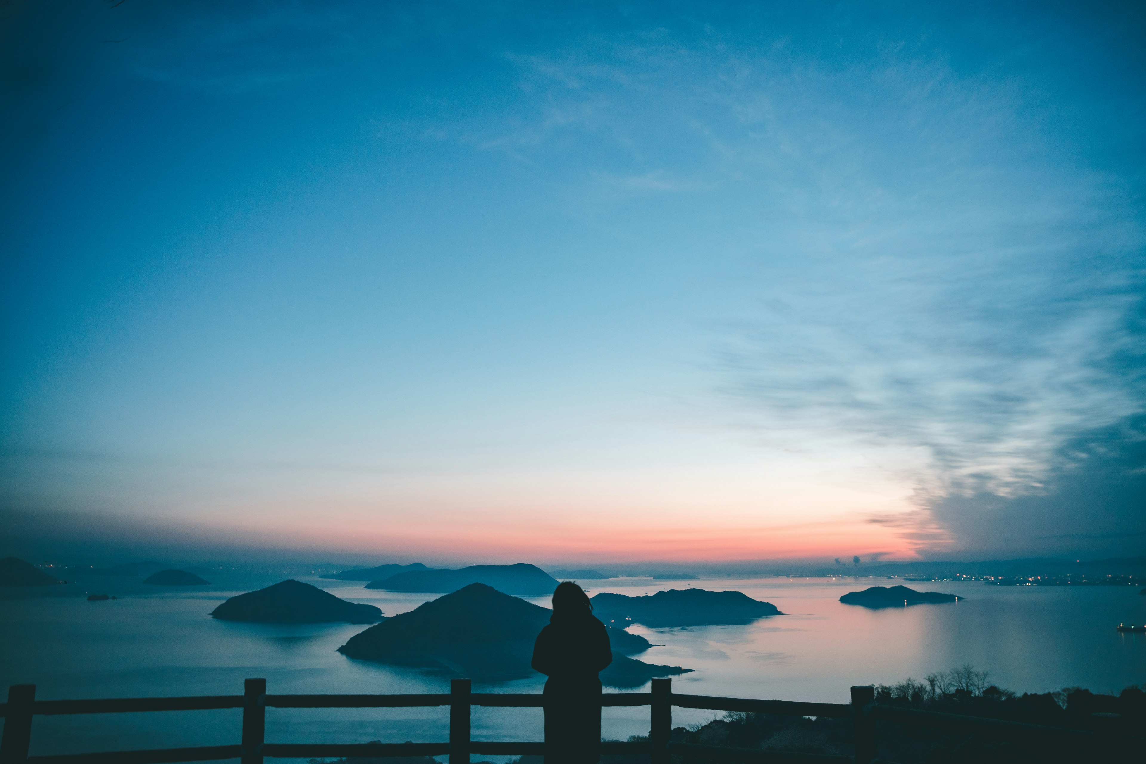 Silhouette einer Person vor einem blauen Himmel und einem Sonnenuntergang über dem Meer