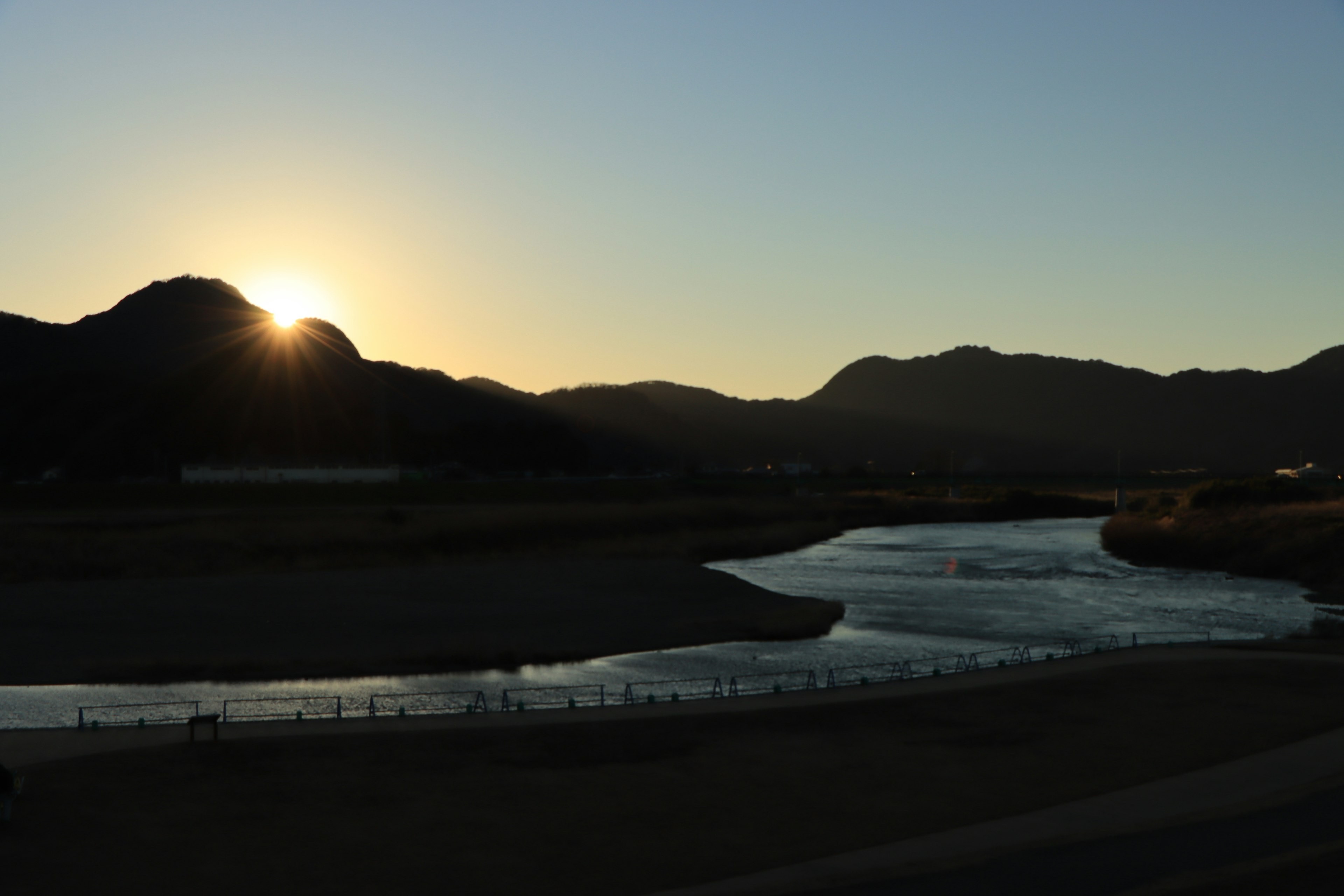 夕日が山の背後に沈む風景と川の流れ