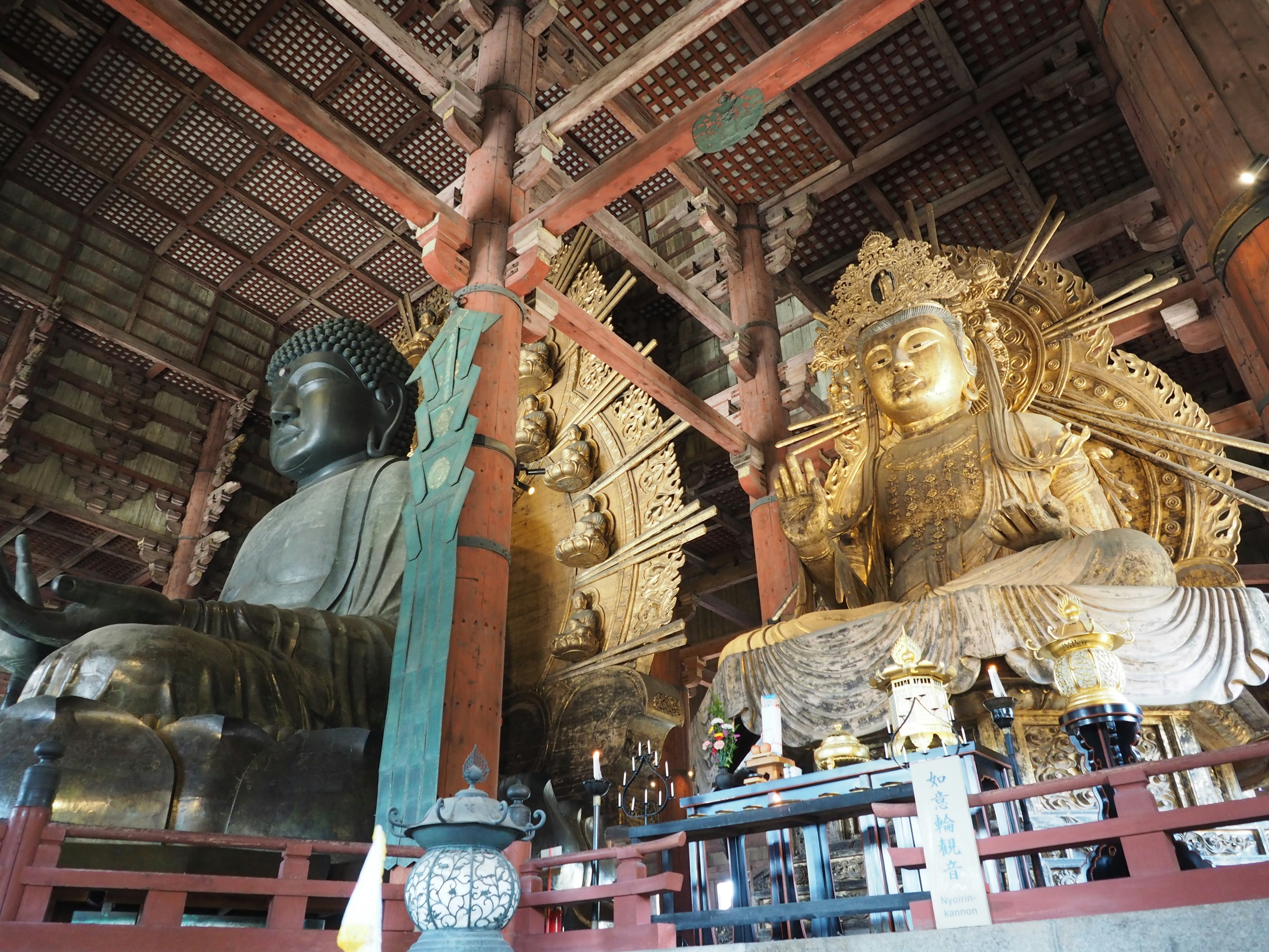 Interior of a temple featuring a large Buddha and a Kannon statue